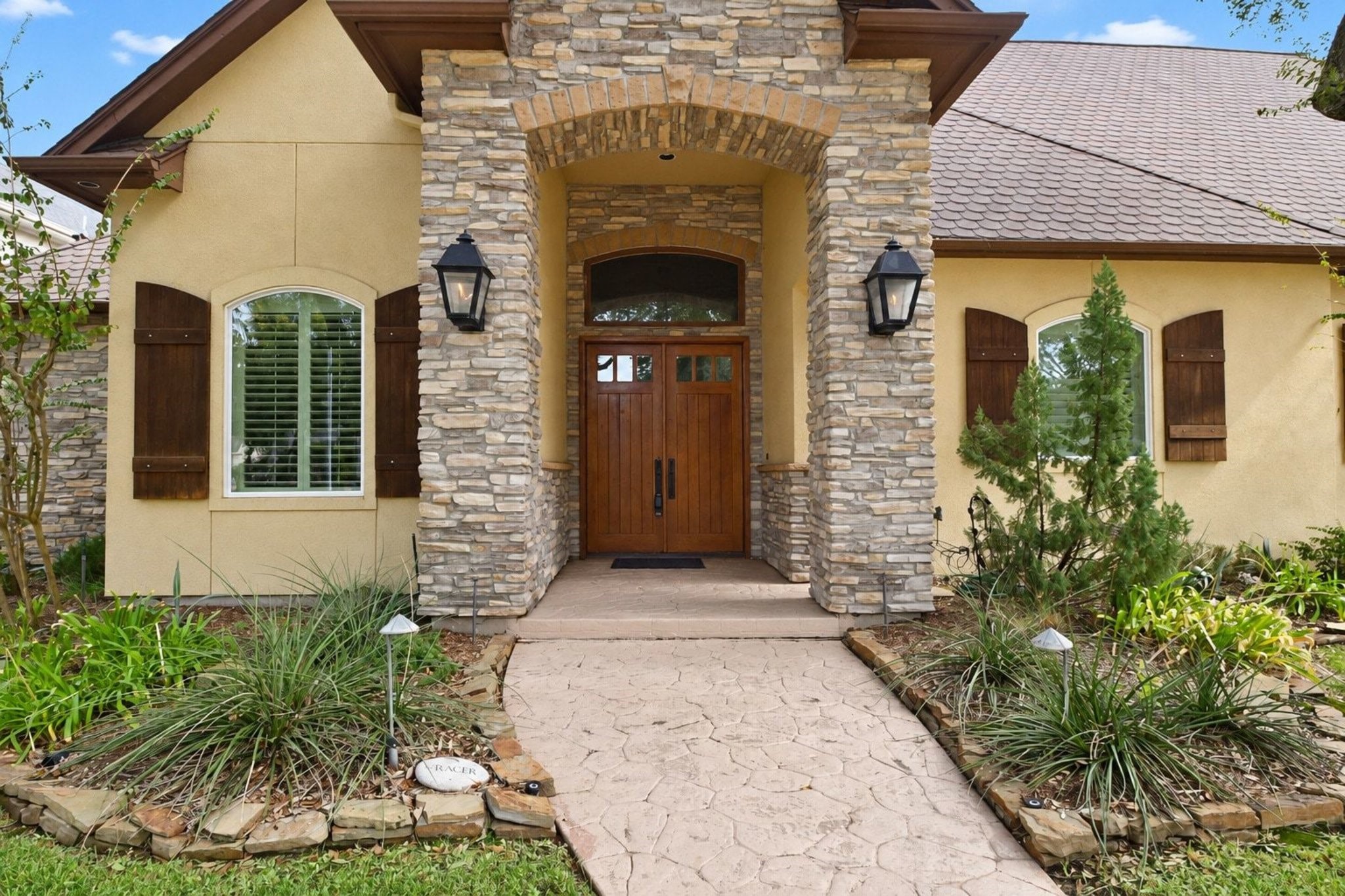 Beautiful stone entrance with custom iron detailing and professional landscape lighting. This grand foyer sets an elegant tone for the entire home, showcasing meticulous craftsmanship and timeless architectural appeal!