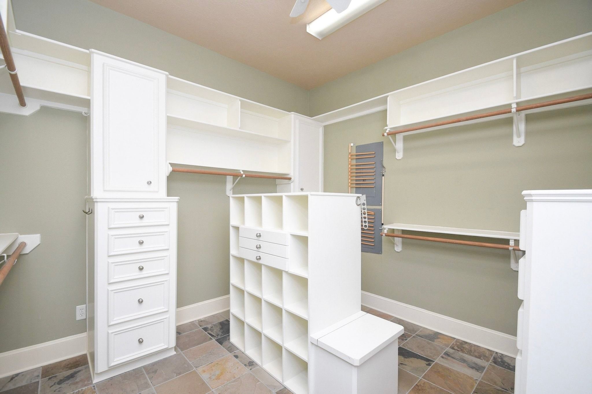 professionally designed walk-in closet that serves as a standout feature of the home. The space is meticulously outfitted with custom-built wooden shelving, integrated organizers, and specialized storage solutions, providing an exceptional level of organization and luxury that maximizes every square inch of the room!