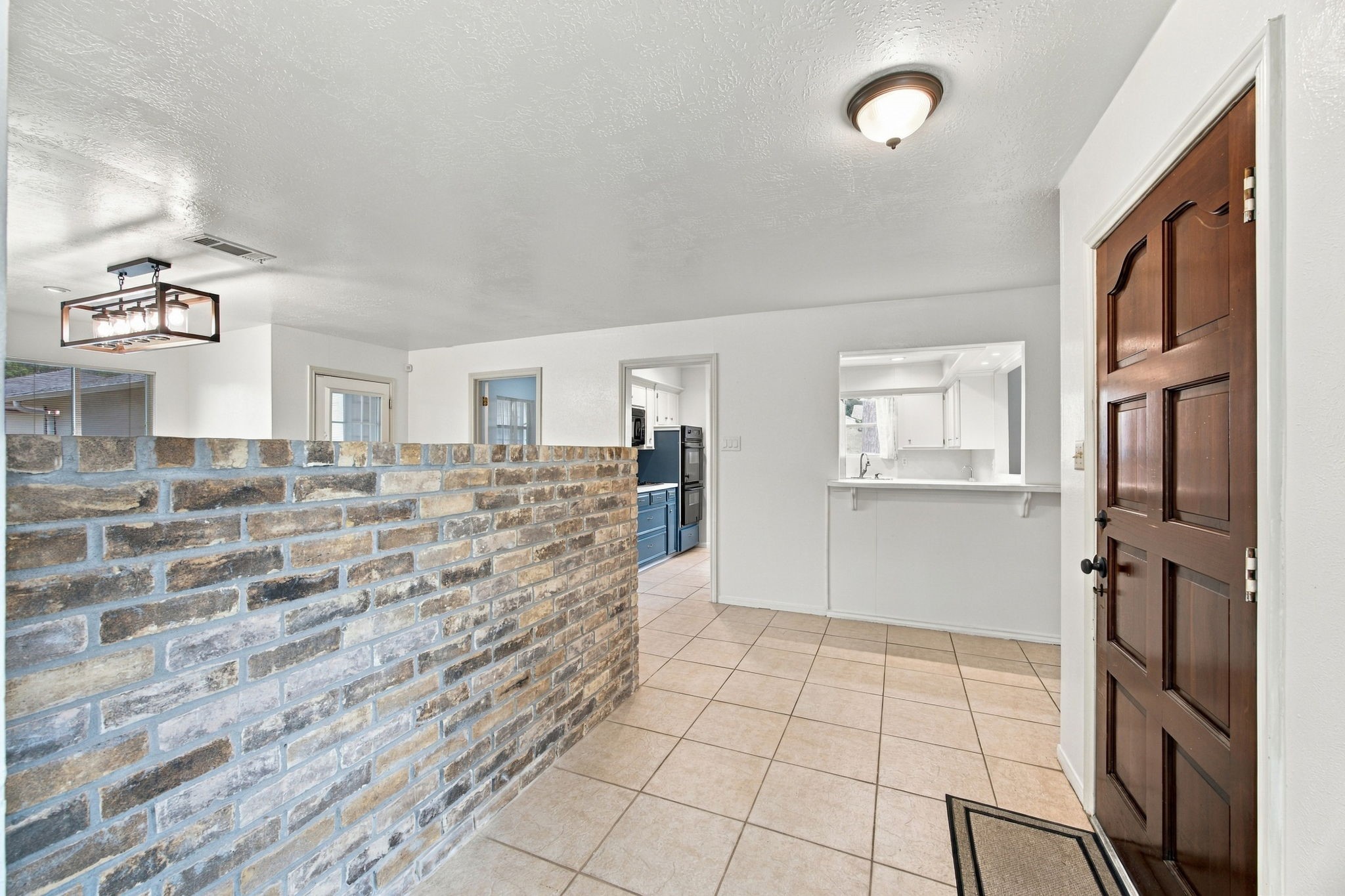 Guests are greeting into this foyer with a brick entrance.  The dining room is on the other side of the wall.