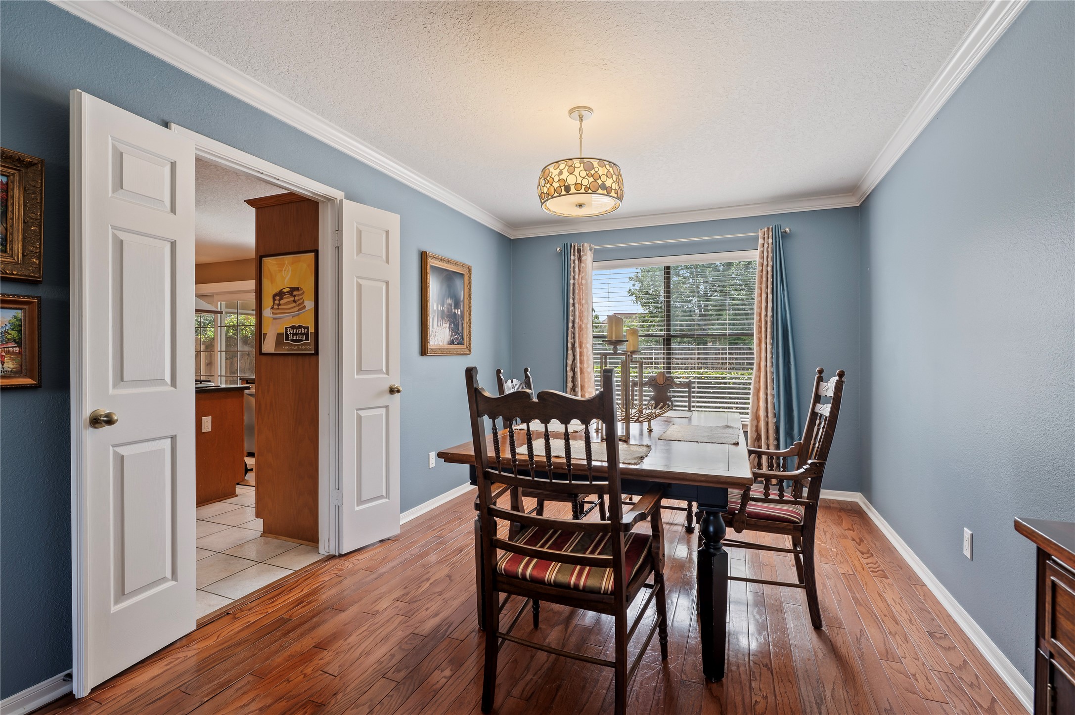 The formal dining room features crown molding, hardwood floors and French doors to the kitchen.