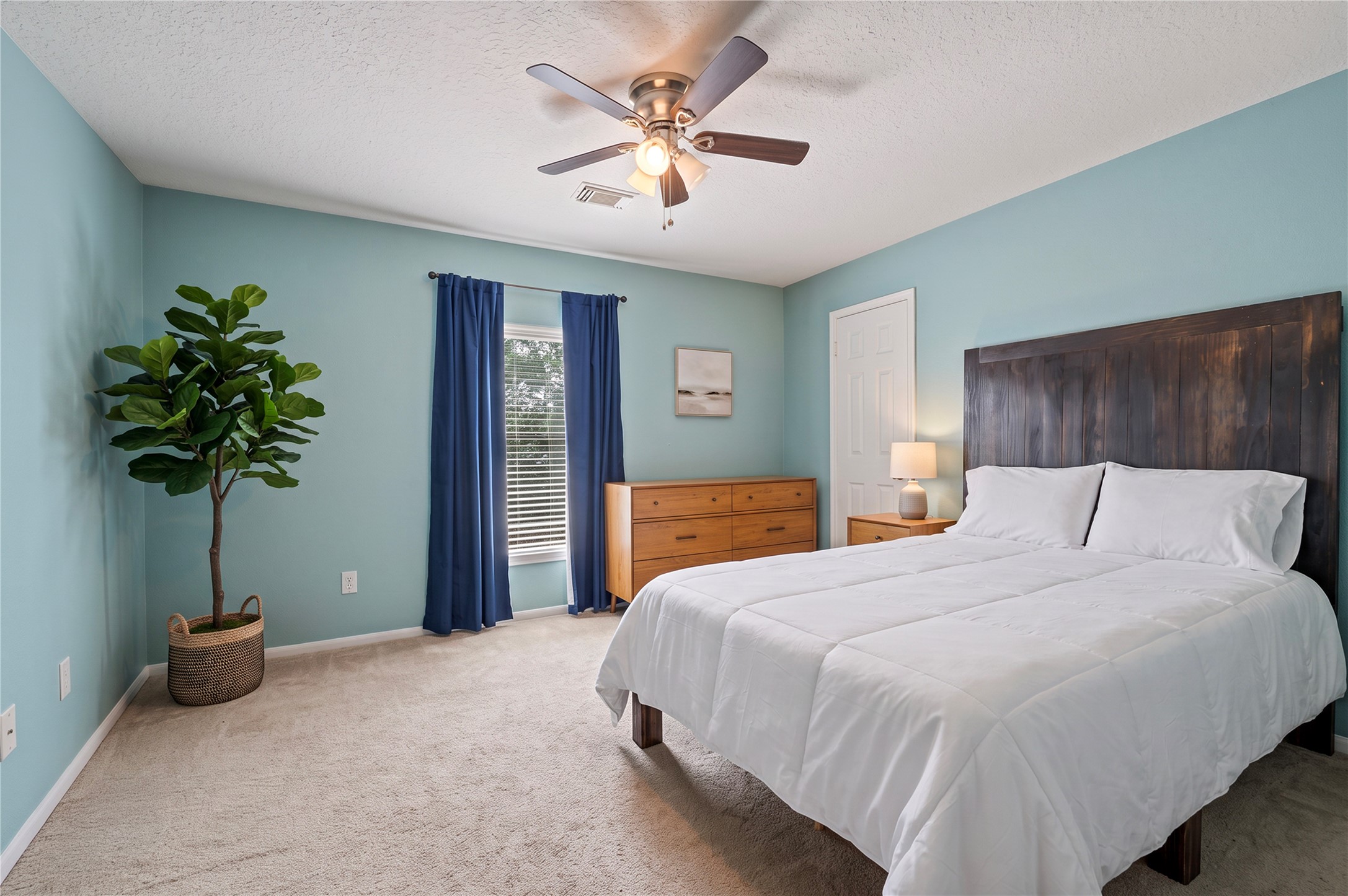 Another spacious bedroom with a ceiling fan and soothing colors.