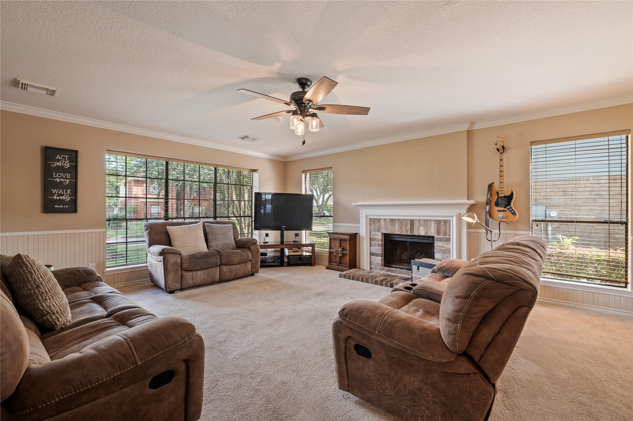The family room is right off the kitchen with a fireplace, bead board and a wall of windows.