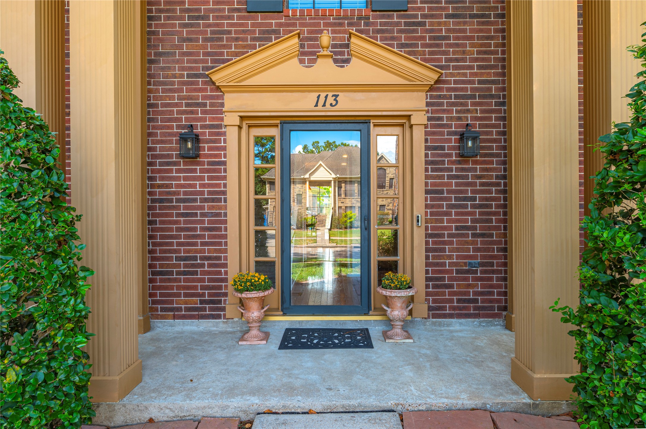 A grand entry welcomes you home, featuring a beautiful front door with decorative sidelights, classic brick framing, and elegant architectural detail.