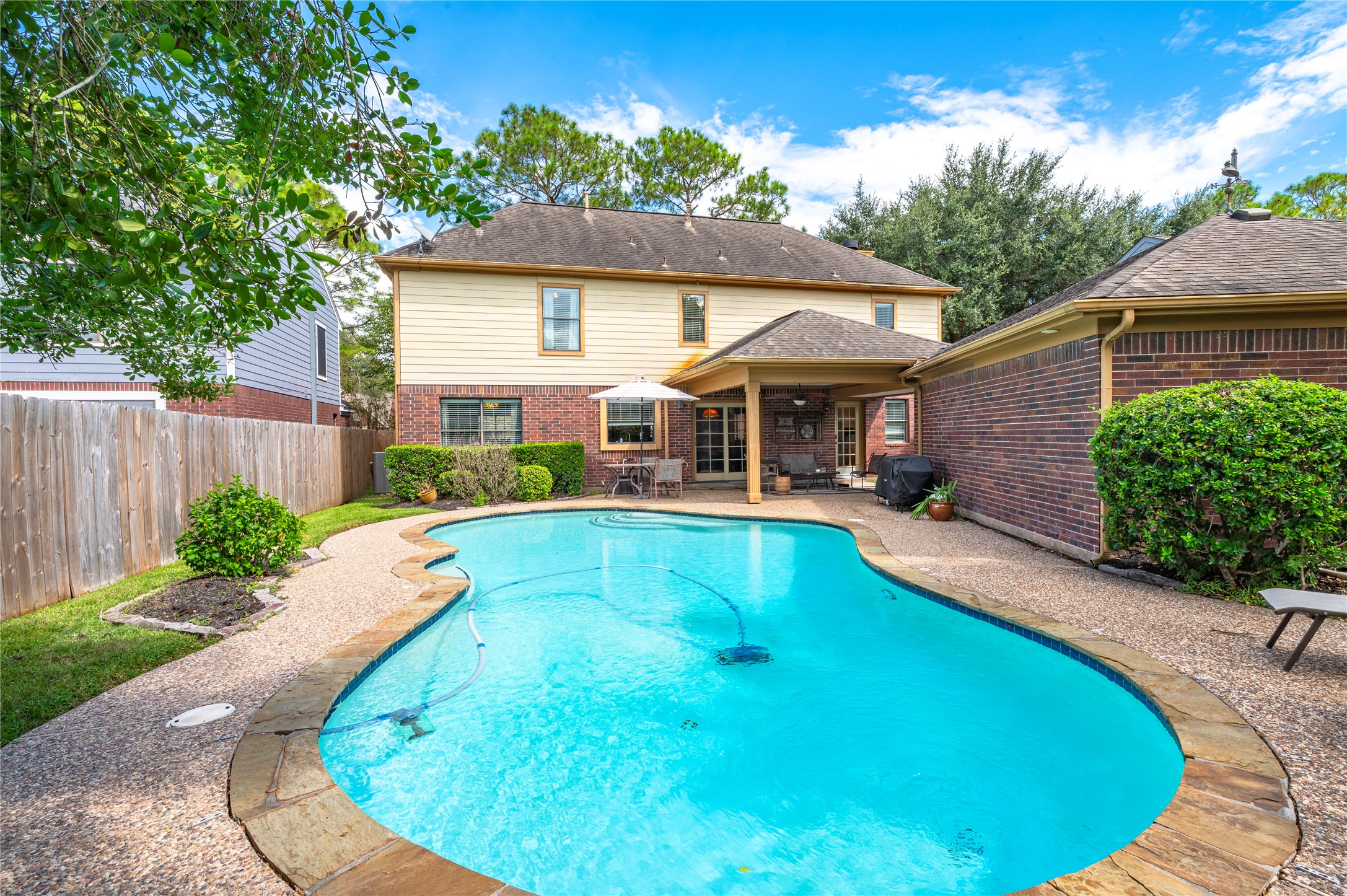 The pool is surrounded by mature trees and a fully fenced backyard.