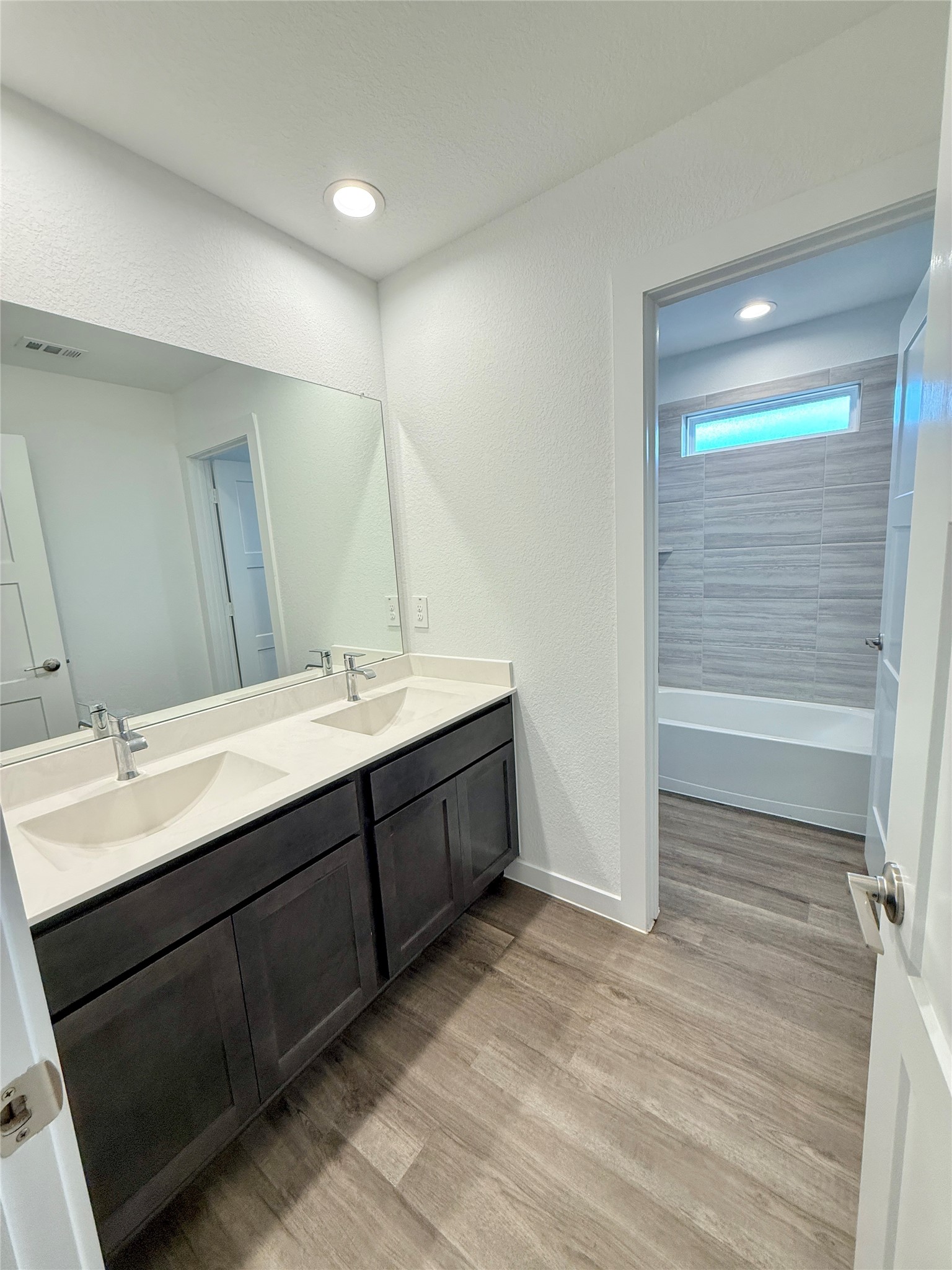 Convenient upstairs bathroom featuring a double vanity with modern fixtures, complemented by a spacious tub/shower combo
