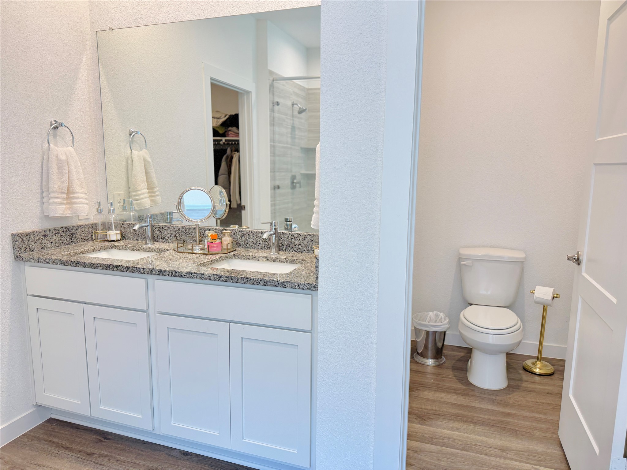 Modern bathroom featuring a spacious dual-sink vanity with granite countertops, ample storage, and a separate toilet area for added privacy