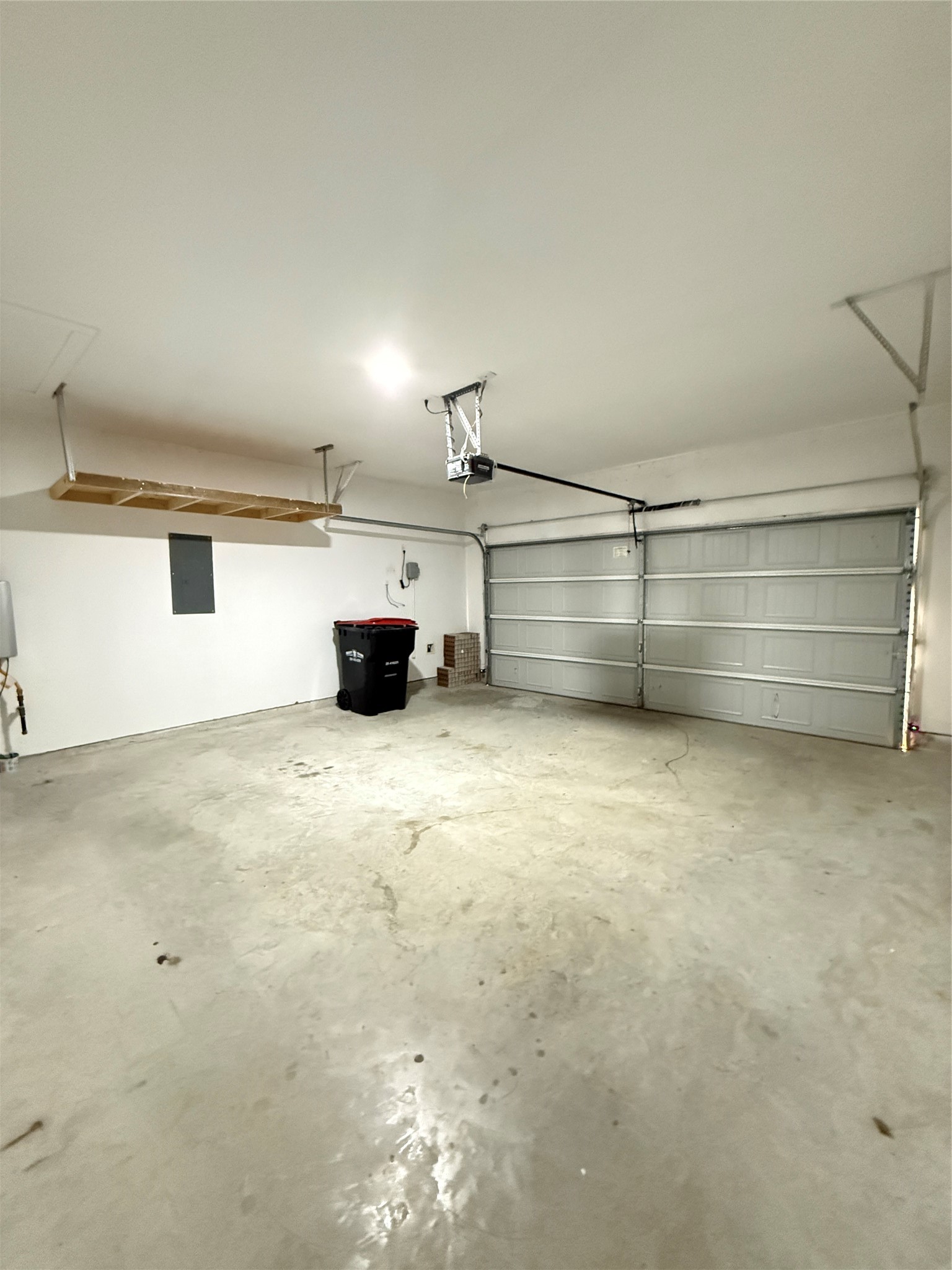 Spacious two-car garage featuring a clean, polished concrete floor, ample overhead storage