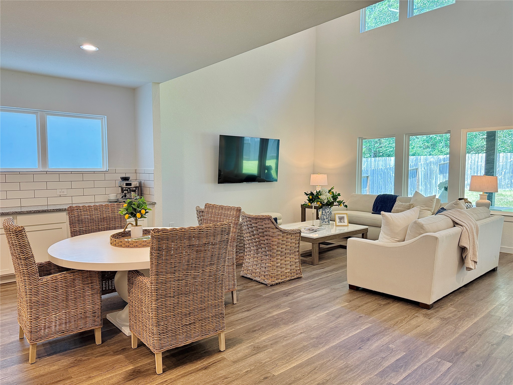 Bright and open living space with high ceilings, featuring a cozy dining area with large windows