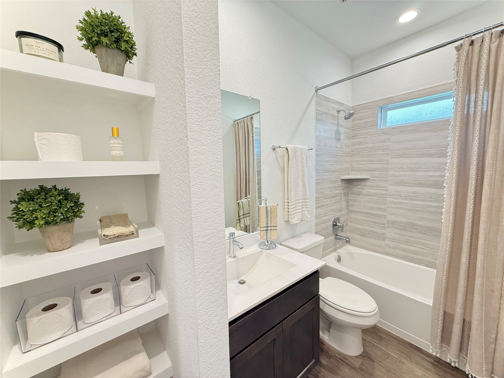 Bright and modern bathroom featuring a sleek vanity, tiled shower, and convenient built-in shelving for storage.