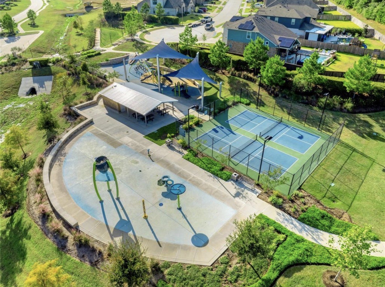 Neighborhood park featuring a splash pad, shaded playground, picnic tables, tennis courts and walking paths.