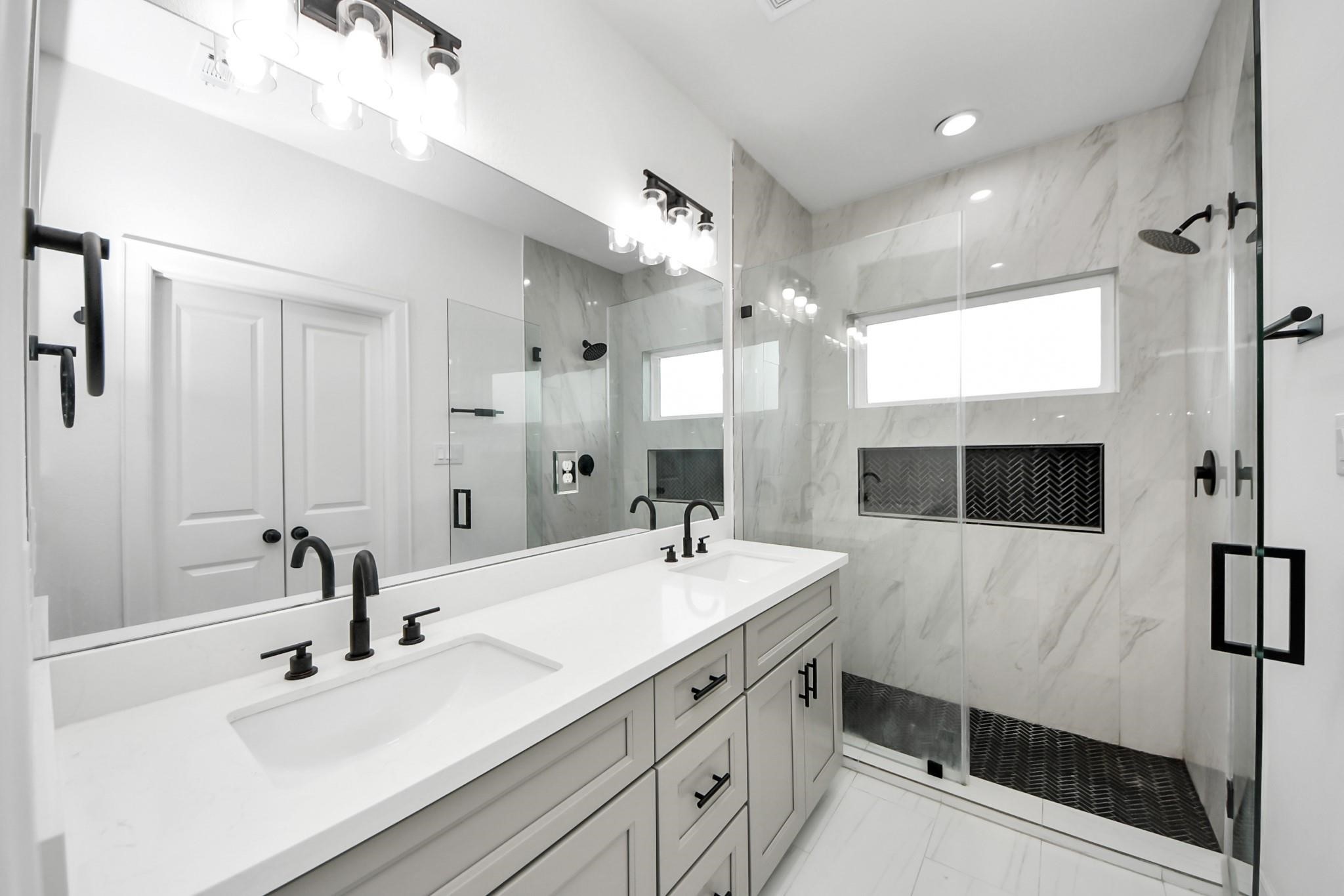 A frameless glass walk-in shower with marble-look tile and black herringbone accents makes a bold design statement. A frameless glass walk-in shower with marble-look tile and black herringbone accents makes a bold design statement.