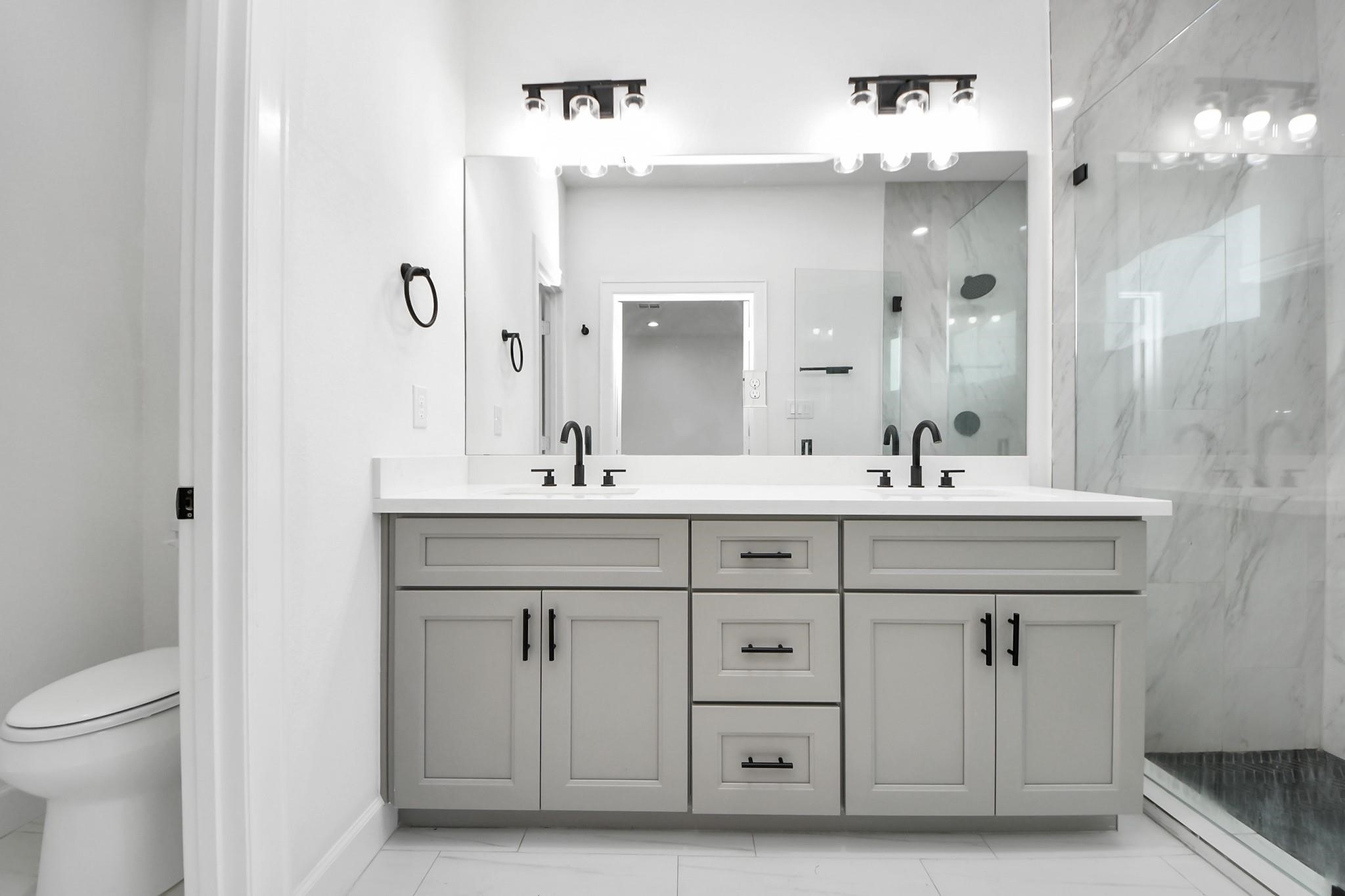 Double vanities with quartz counters and undermount sinks provide both elegance and efficiency.