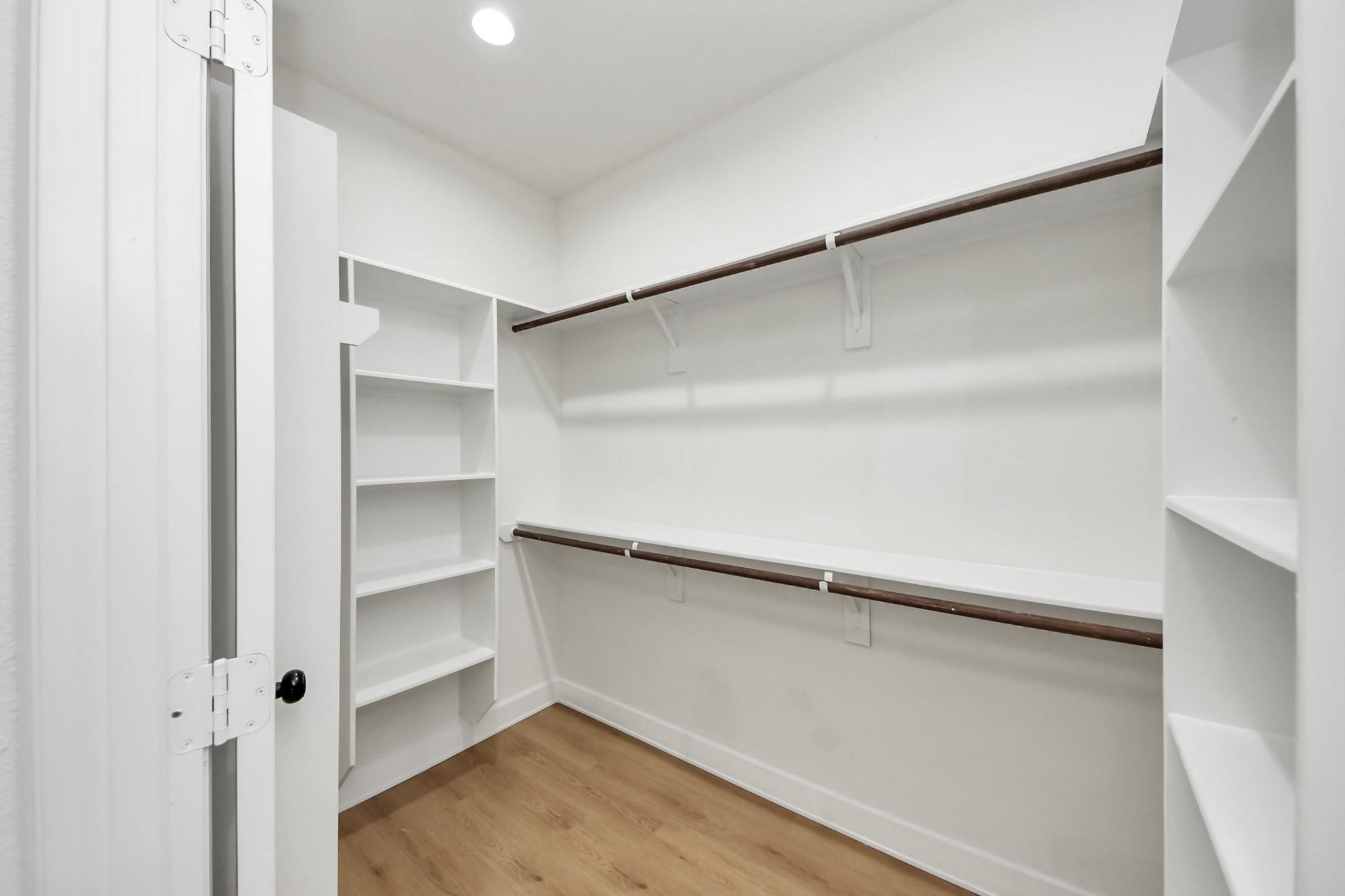 This spacious walk-in closet features built-in shelving and dual hanging rods for maximum organization.
