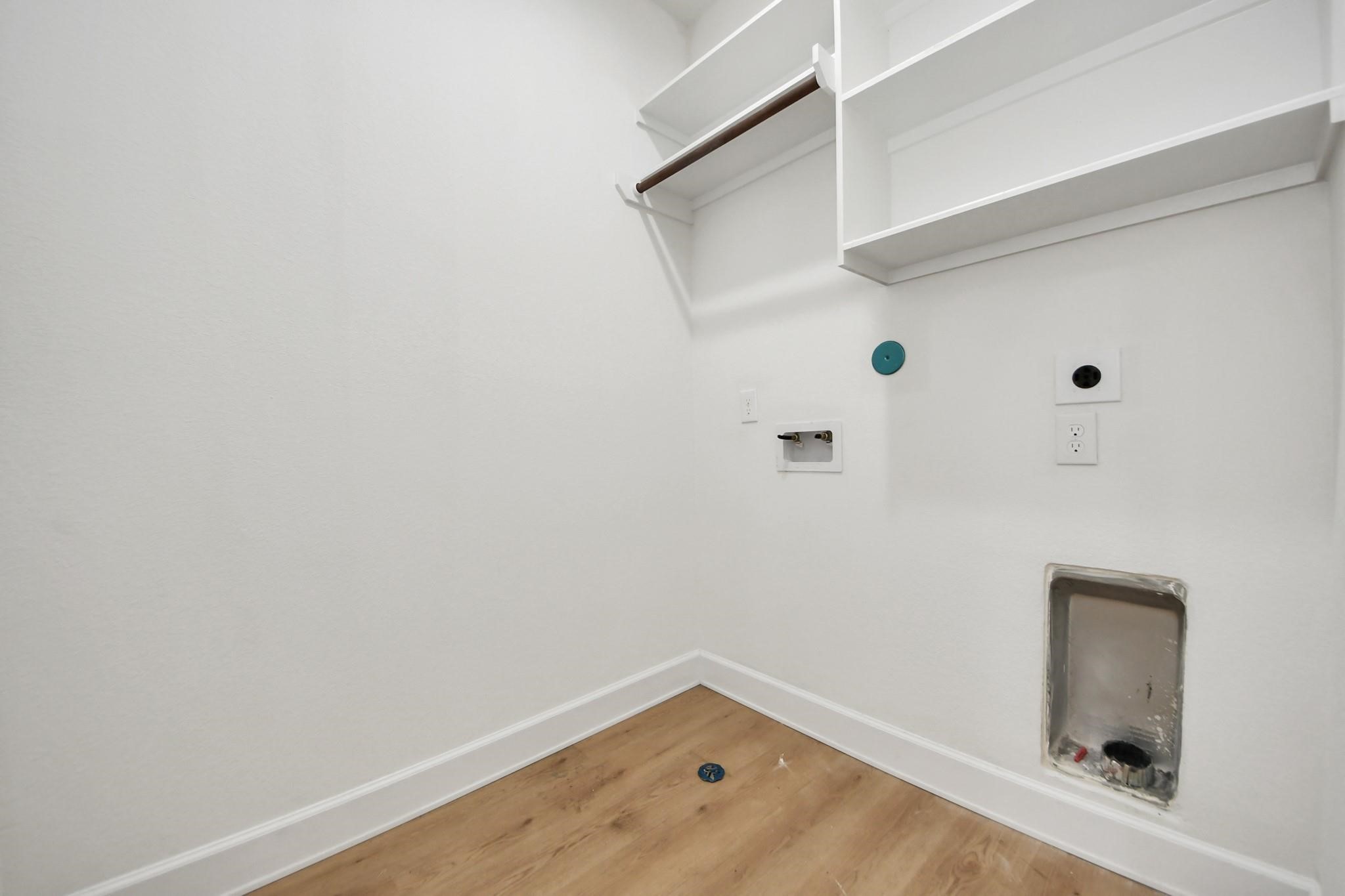 Dedicated utility room includes full-size washer and dryer connections with overhead shelving for easy organization.