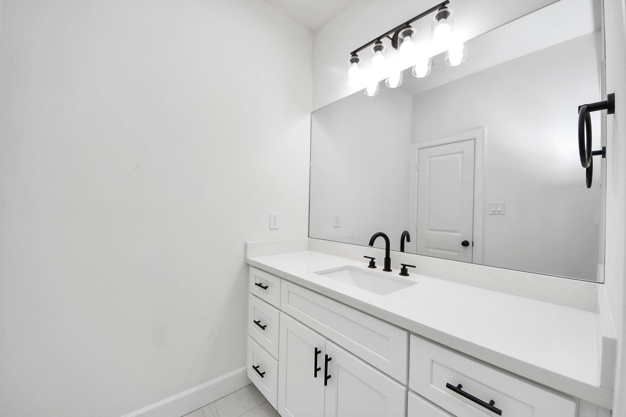 The quartz countertop and undermount sink provide a seamless, easy-to-clean surface in this secondary bathroom.