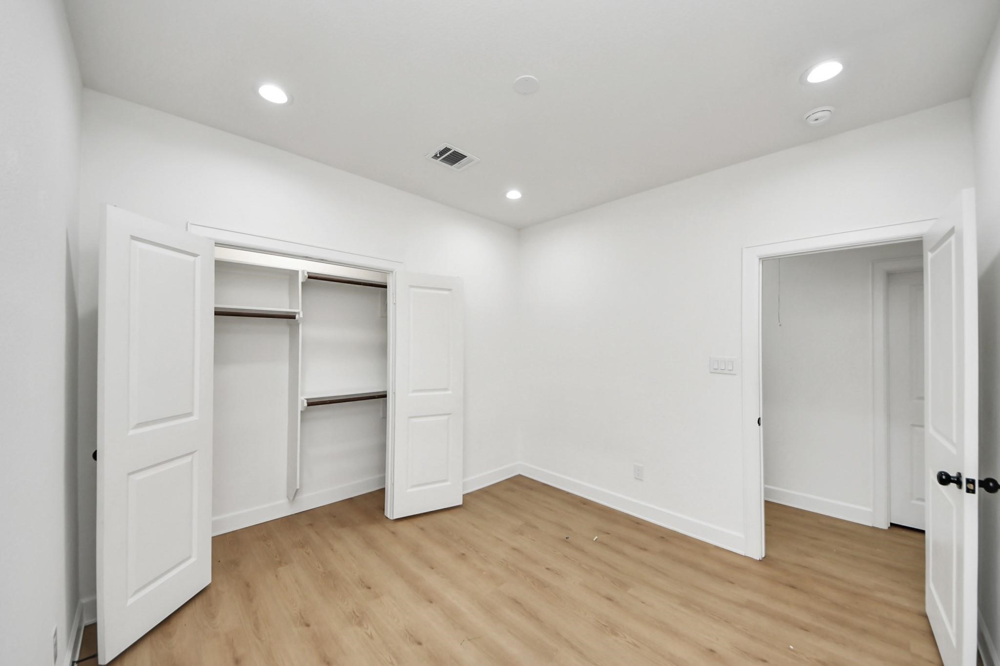 Bright and airy, this secondary bedroom features recessed lighting and a large closet with double doors.