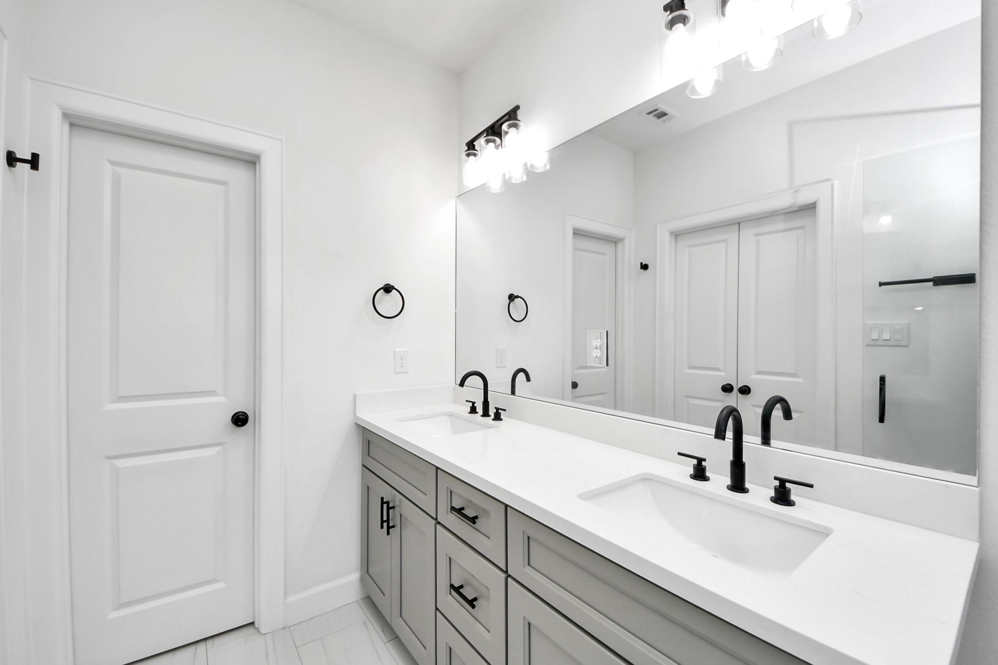 Designer-selected lighting fixtures and full-length mirror elevate this primary bath's functionality and style.