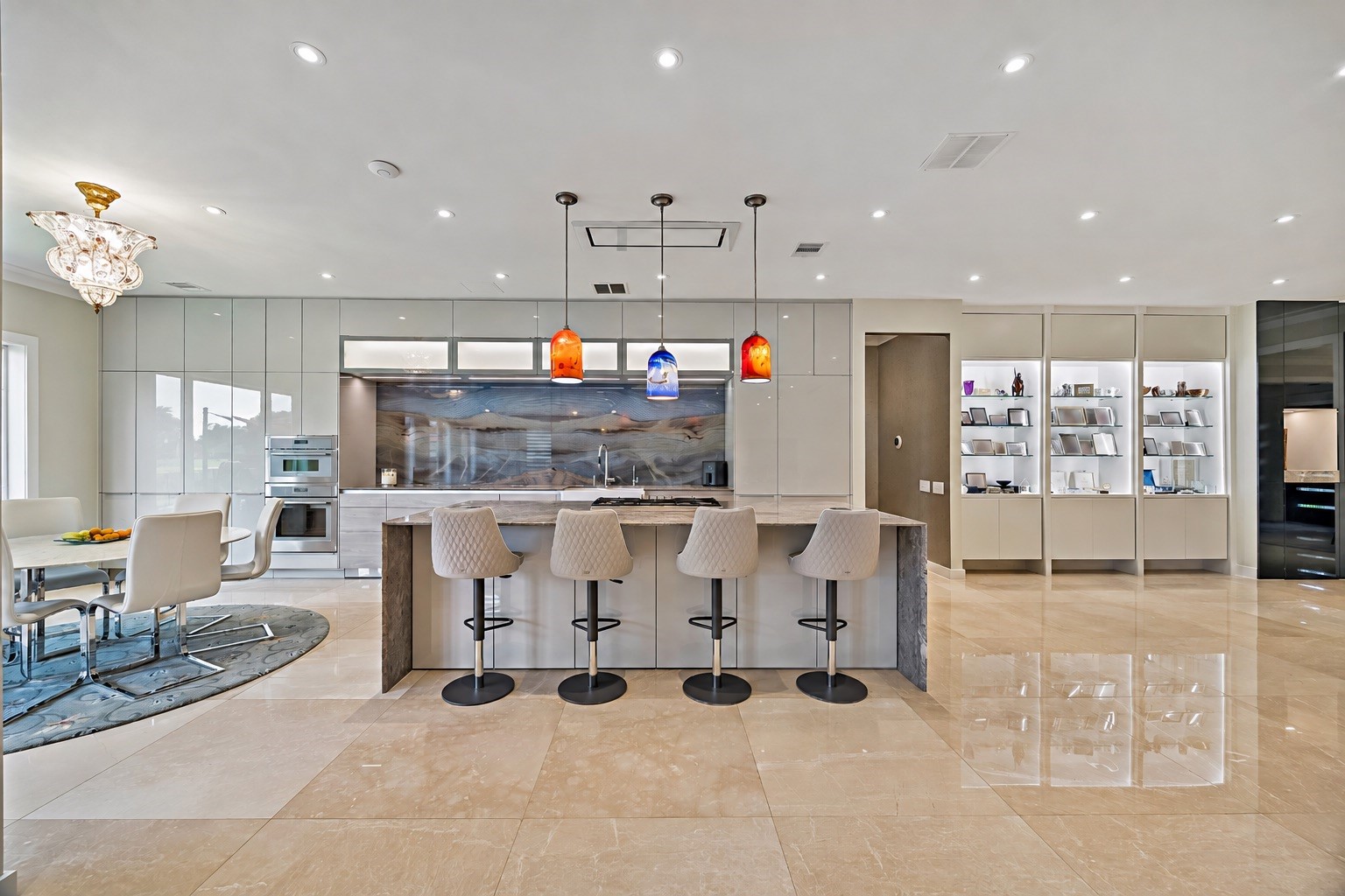 A beautifully appointed kitchen featuring a substantial center island with cooktop, breakfast-bar seating, sleek cabinetry, and contemporary pendant lighting. Designed to connect seamlessly with the adjacent family room and breakfast area.