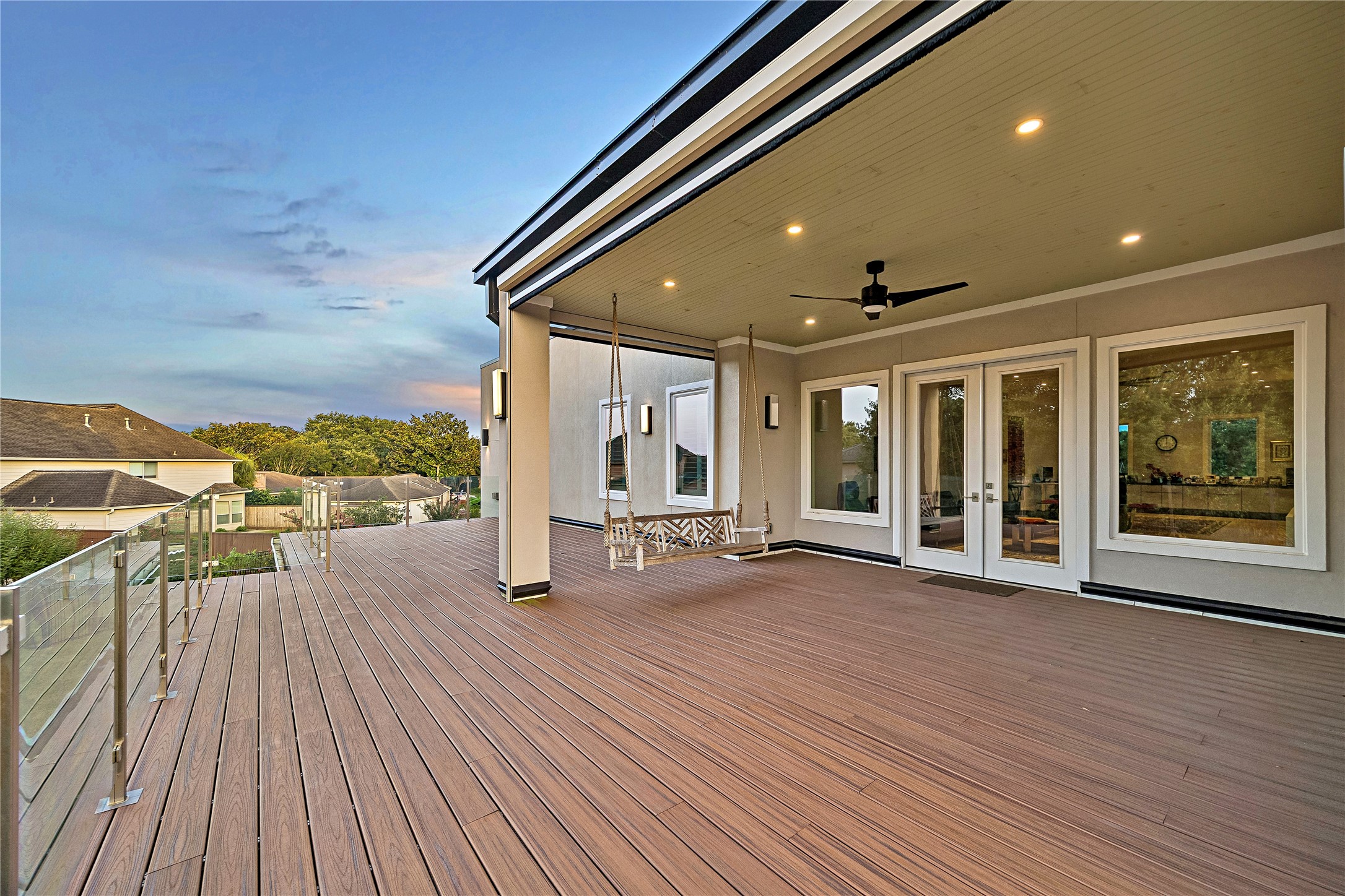 An extraordinary elevated outdoor living space overlooking Sugar Creek Country Club's manicured fairways. The expansive 712 square-foot terrace features transparent glass railings, covered seating areas, ceiling fans, and exterior solar screens designed to provide shade and comfort while preserving the views.