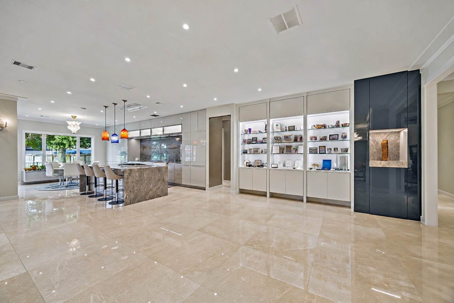 A sweeping view of the home's connected gathering areas, showcasing custom cabinetry, expansive entertaining space, and a thoughtfully integrated kitchen. The open design creates a natural flow between dining, conversation, and everyday living.