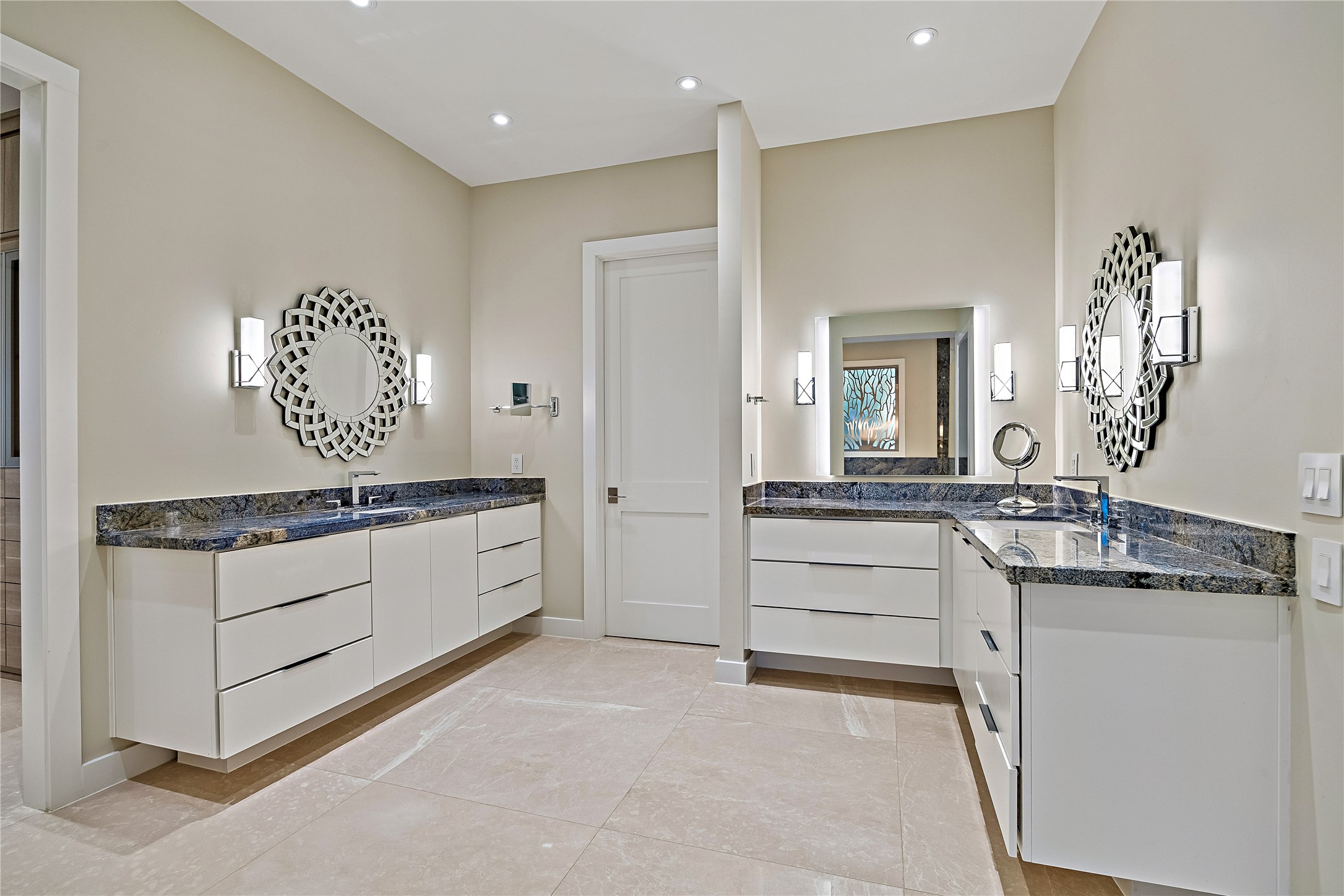 A beautifully appointed primary bathroom featuring separate vanities, generous counter space, decorative mirrors, and refined finishes. The thoughtful layout provides distinct grooming areas within the spacious suite.