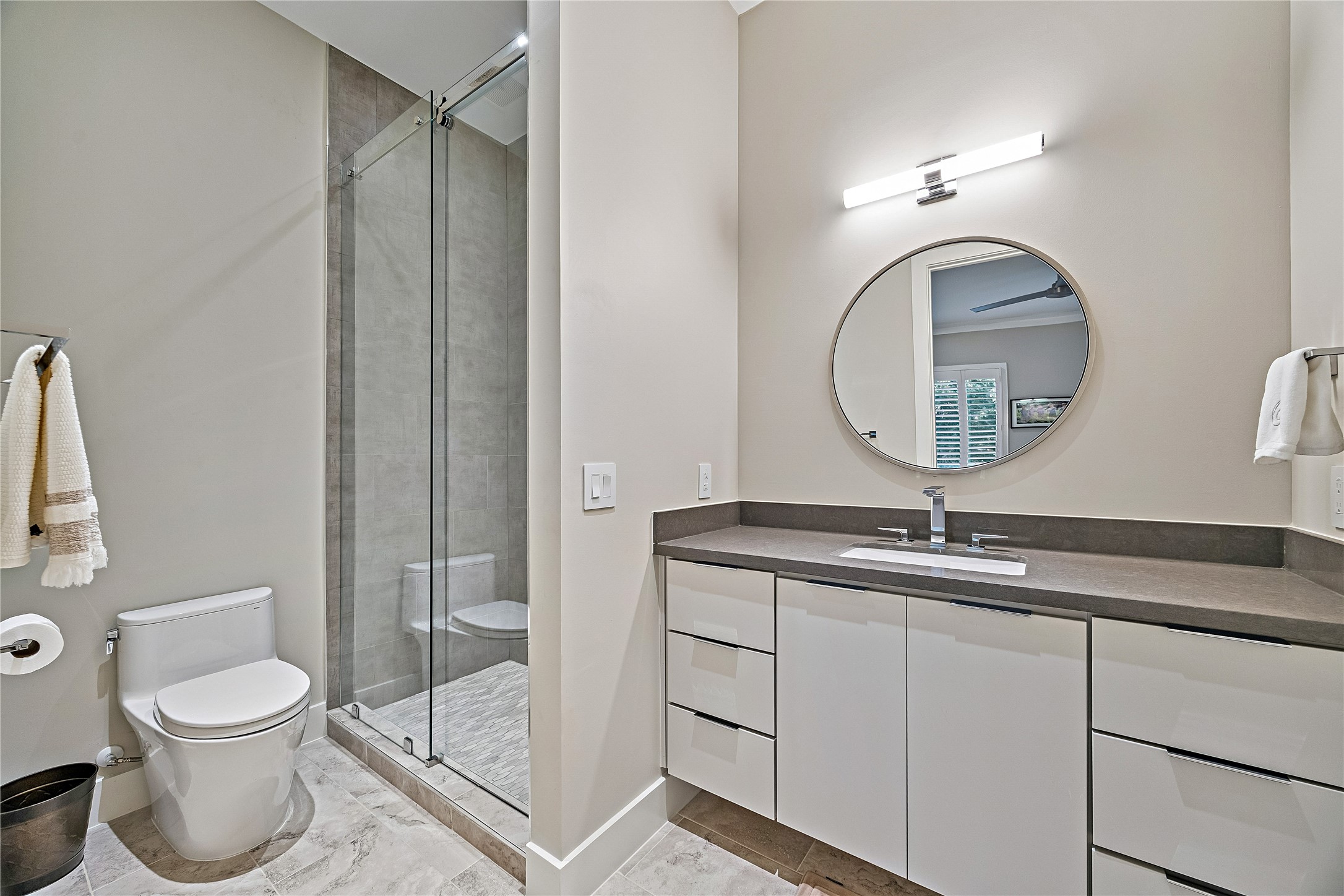 Contemporary bathroom featuring a glass-enclosed shower, streamlined vanity, decorative mirror, and neutral finishes. A thoughtfully designed space complementing the home's secondary bedrooms.