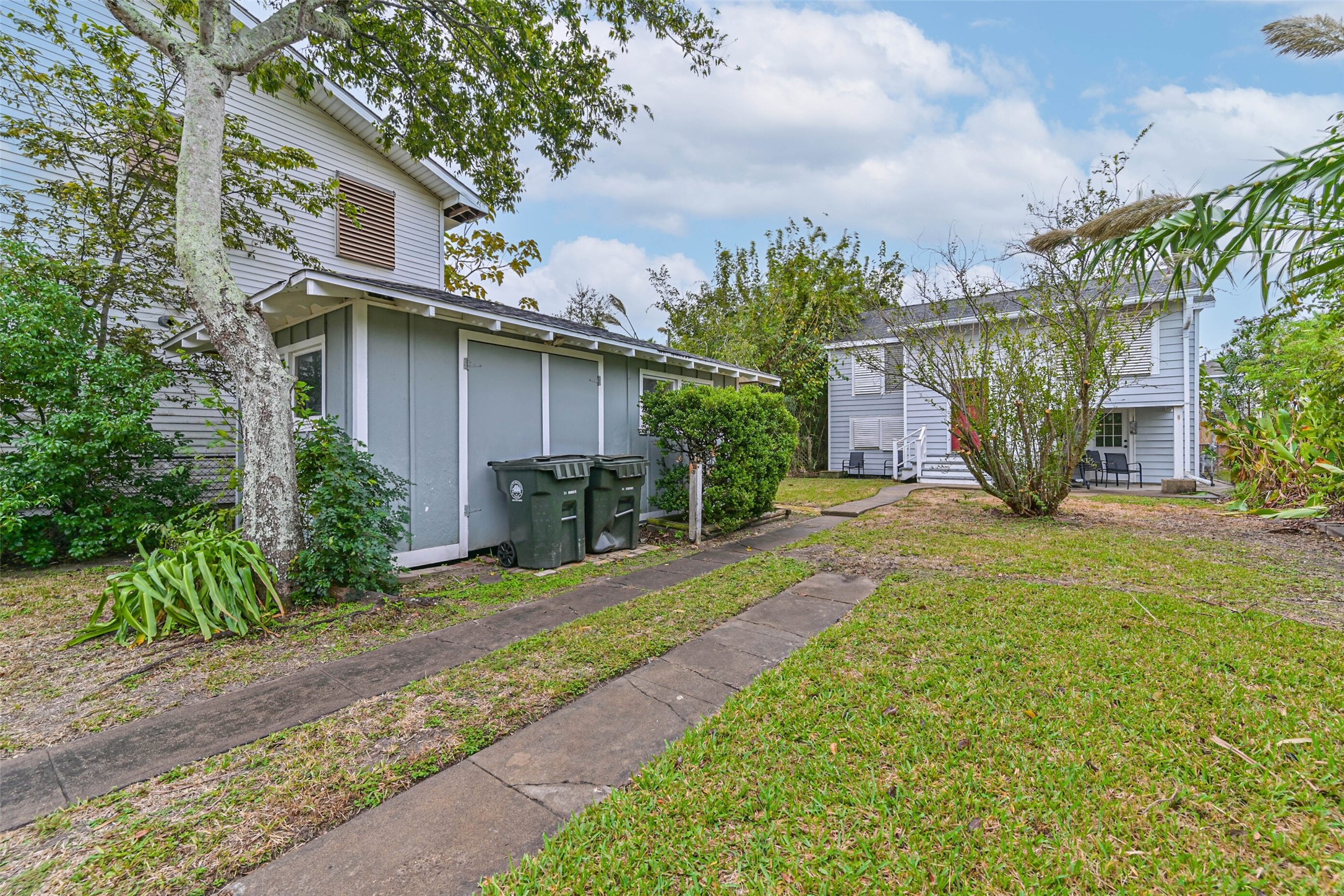 A charming exterior view of the home surrounded by mature trees and greenery, highlighting its relaxed outdoor setting.