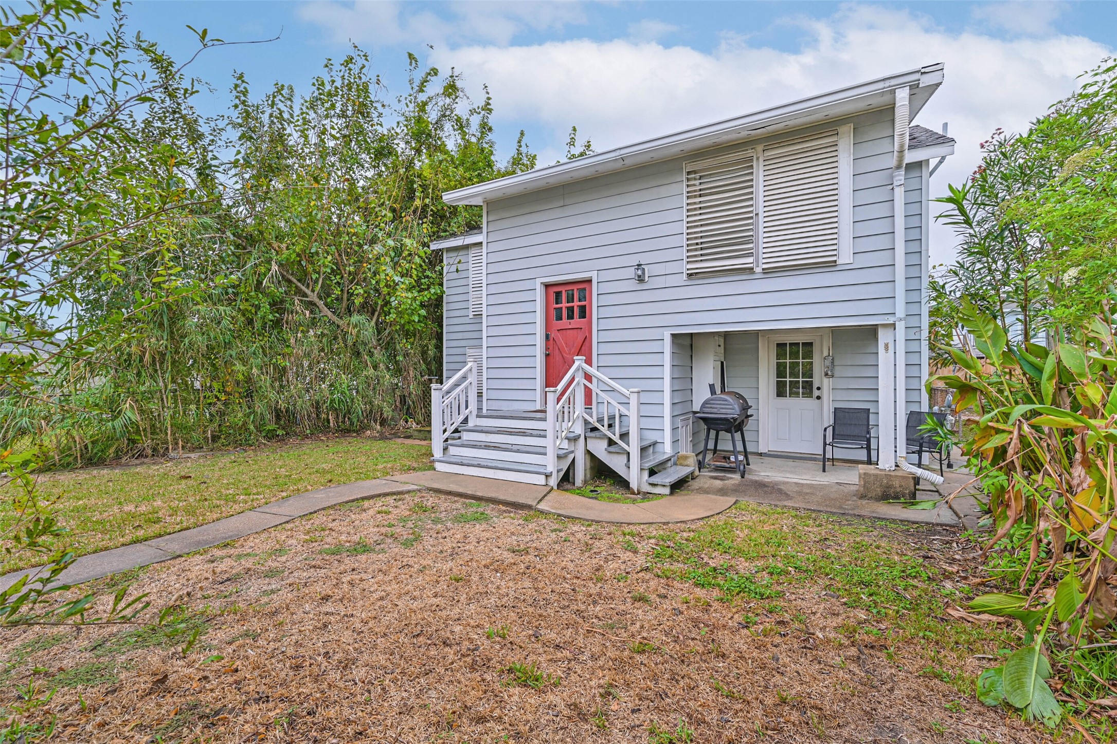 A welcoming exterior view featuring the home's raised entry, red front door, and surrounding greenery.