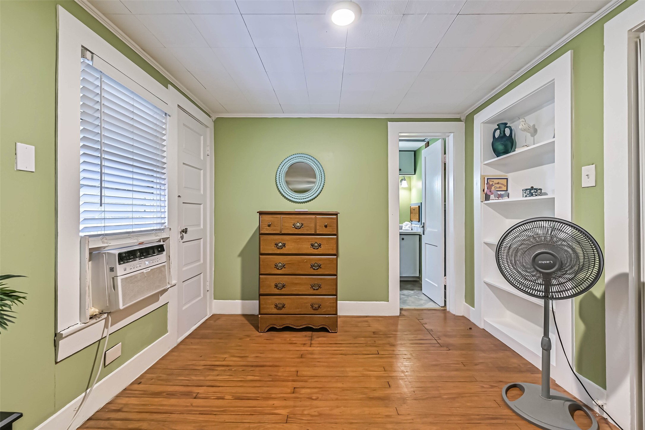 A comfortable bedroom with a dresser and ceiling fan, offering a practical and restful space.