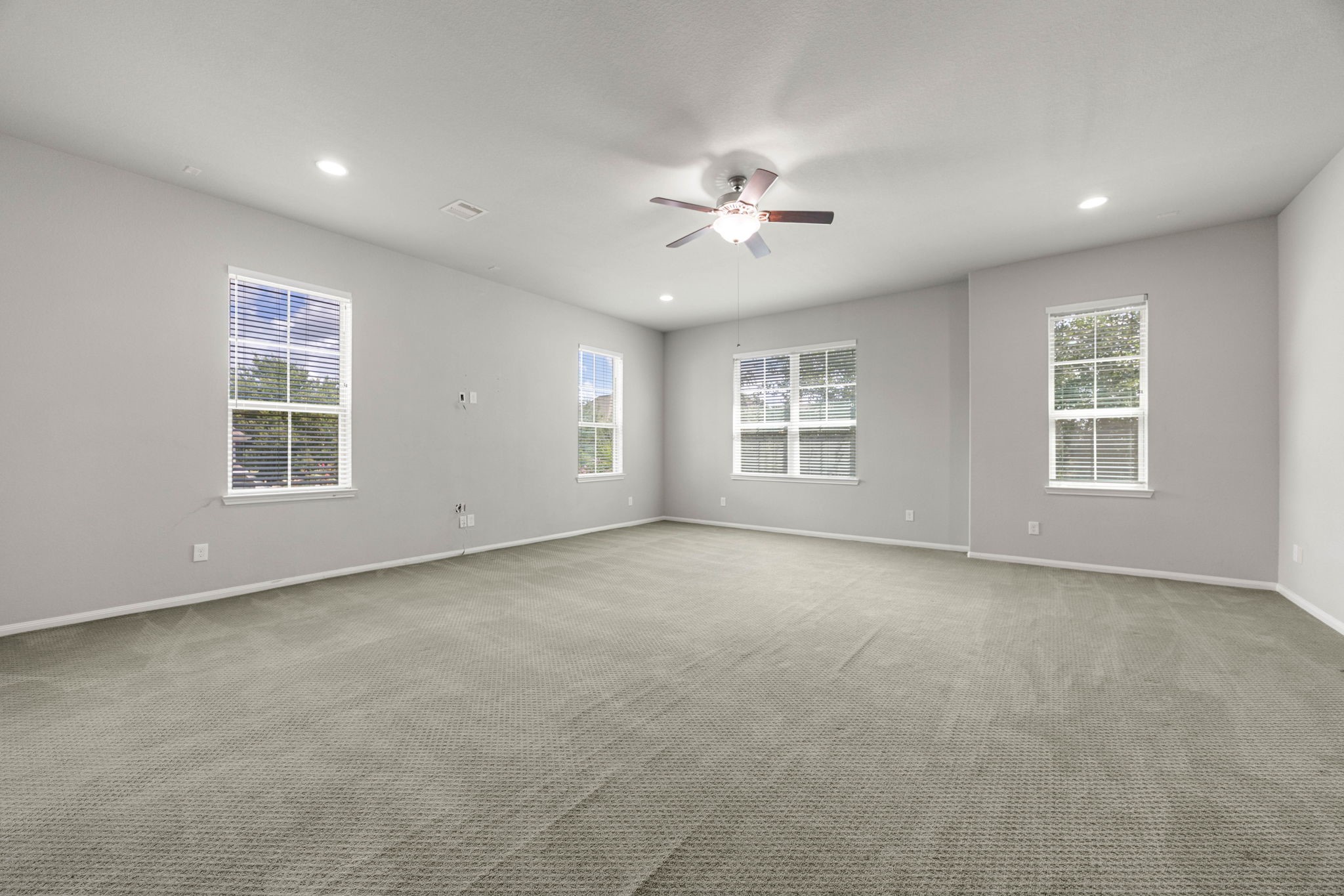 A spacious gameroom offers flexible space for recreation or a second living area, framed by windows on two sides for natural light. V