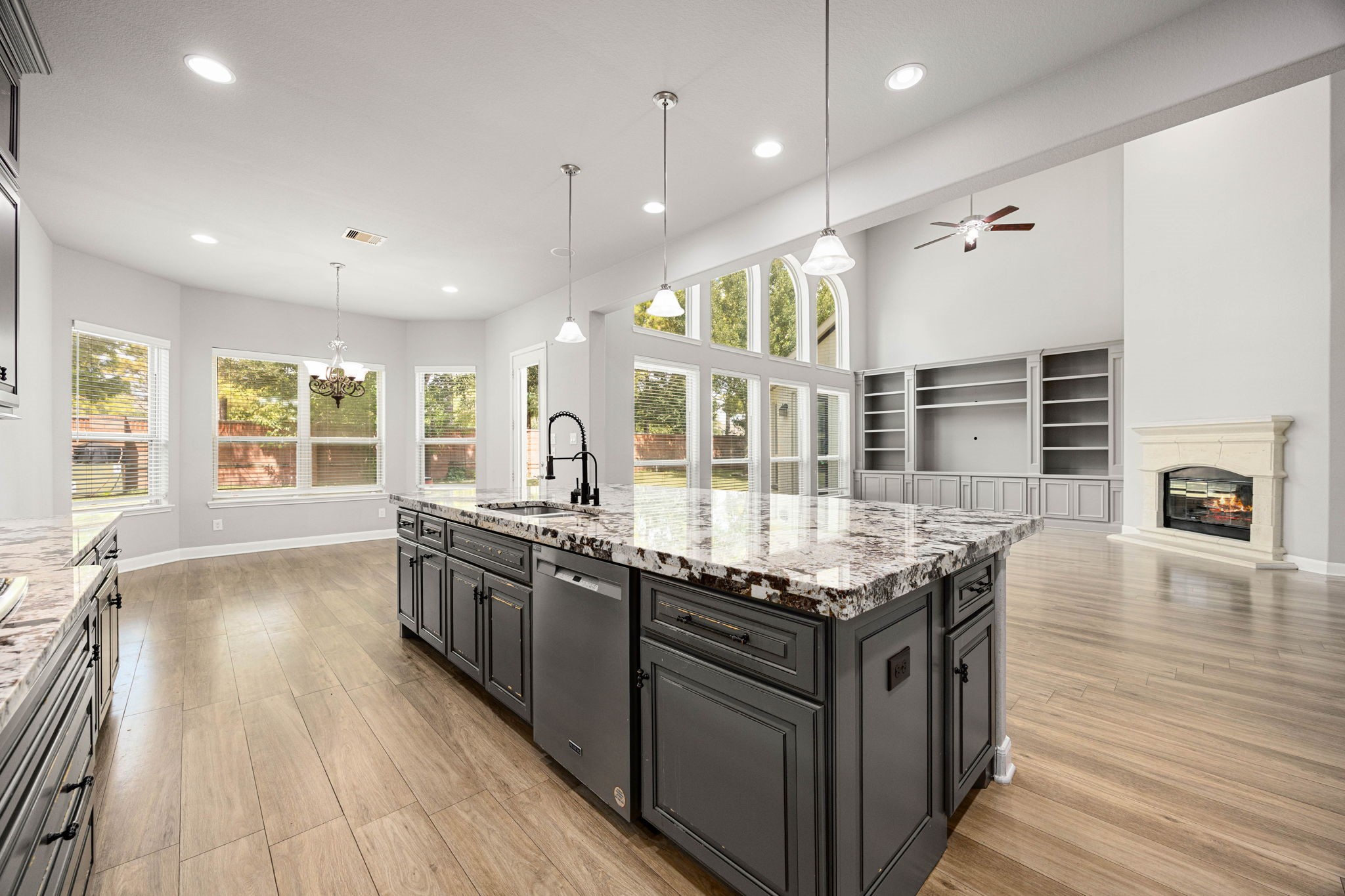 The kitchen's oversized island offers abundant prep space and seating, opening directly to a sunlit breakfast nook and the two-story living area beyond  ideal for both daily life and entertaining.