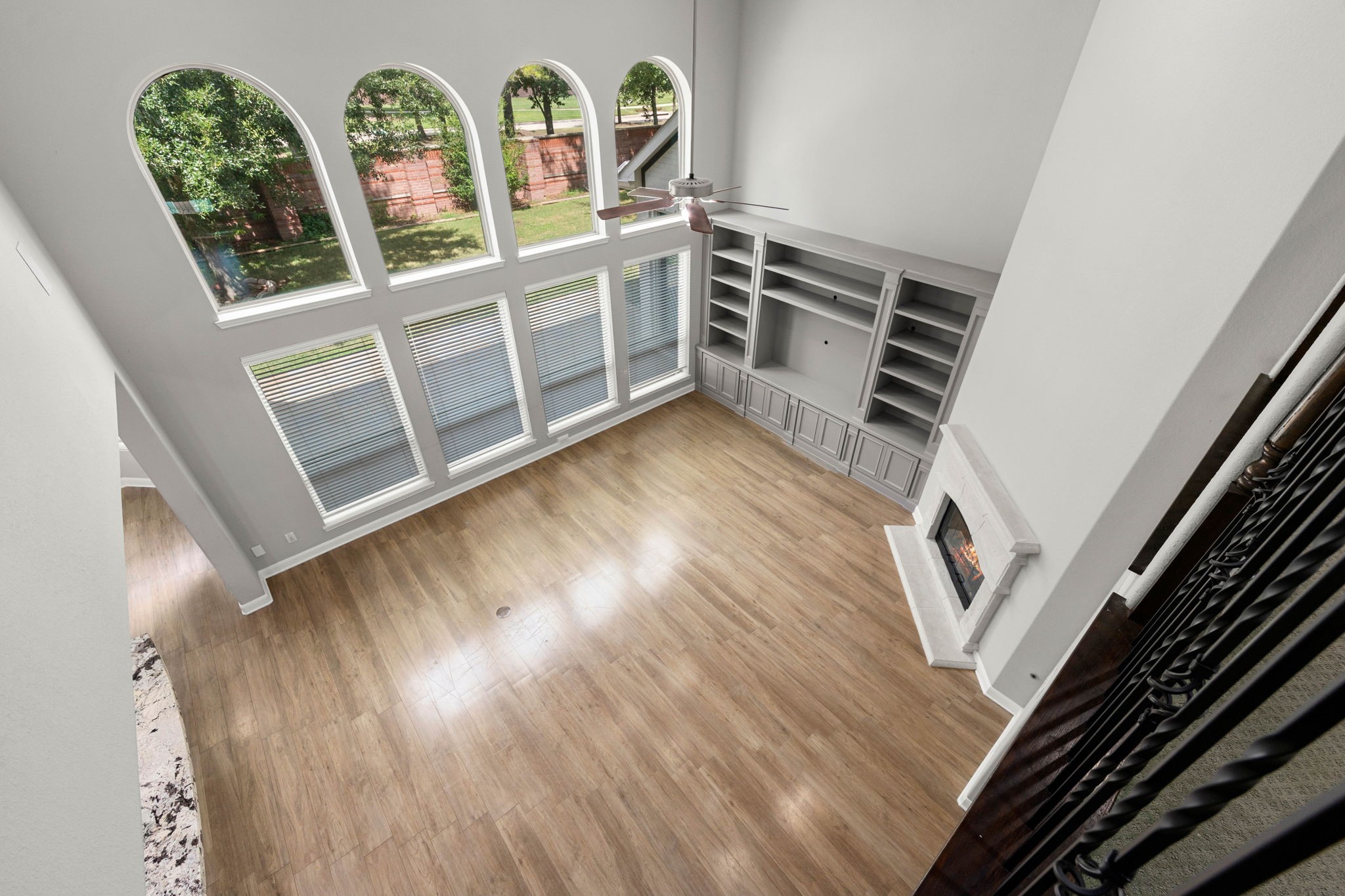 Overlooking the two-story living area from above, this vantage point highlights the arched windows, custom built-ins, and stone fireplace that anchor the main living space.