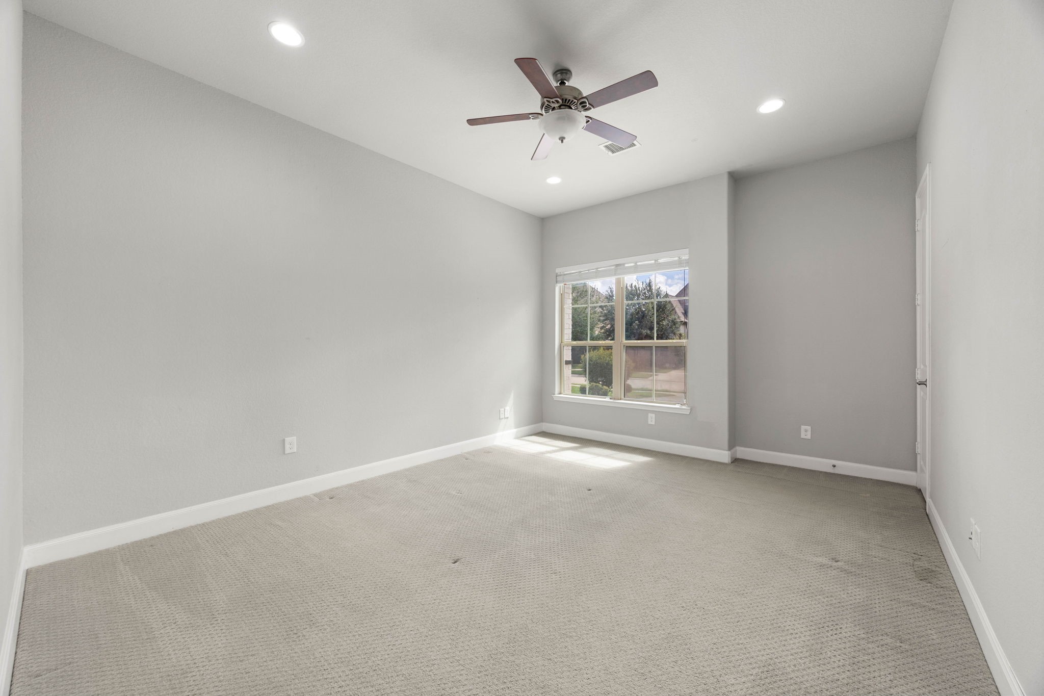 This first-floor secondary bedroom offers plush carpet and a large window with backyard views, making it a flexible option for guests or multigenerational living.