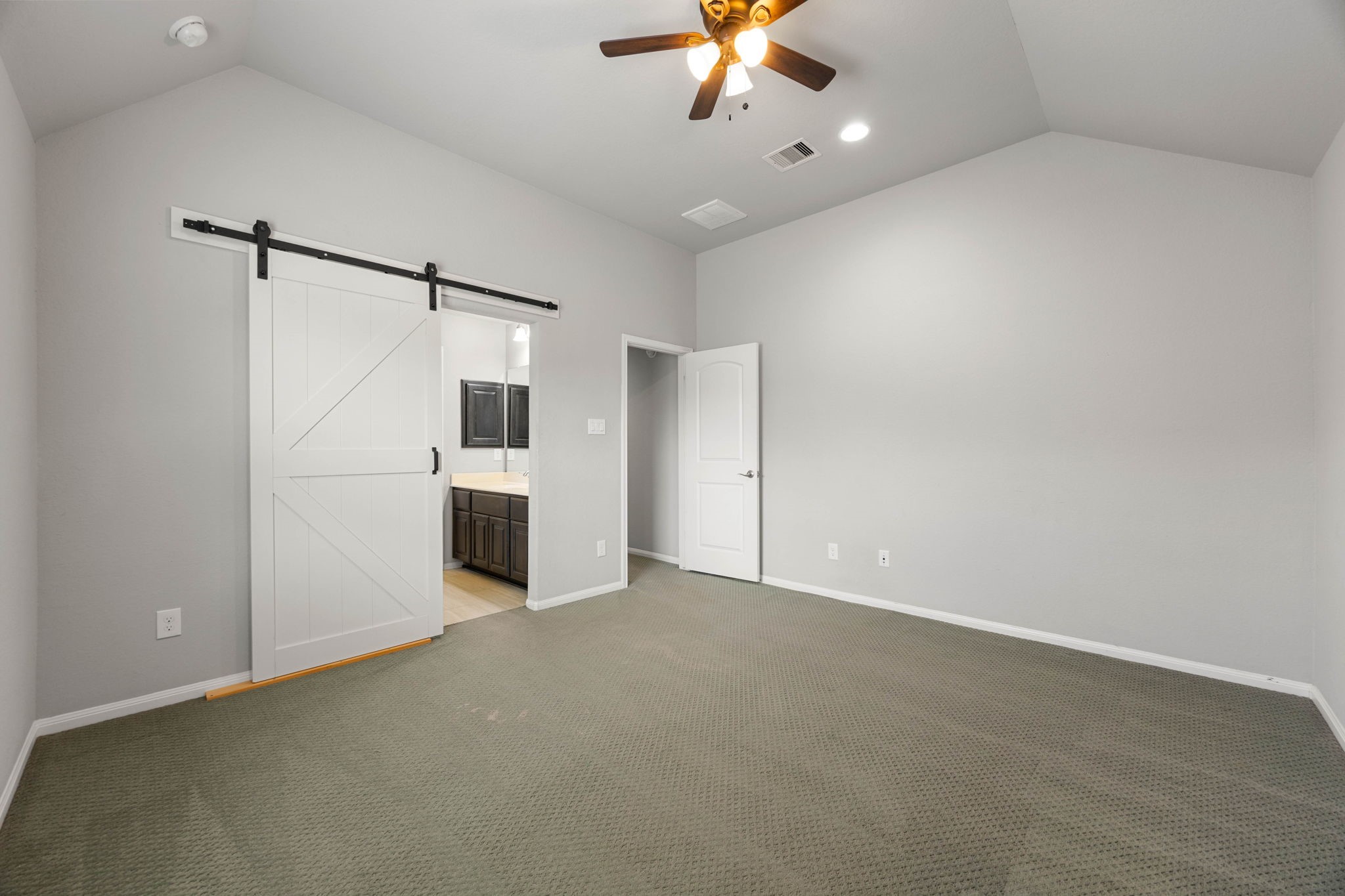 A sliding barn door leads from this secondary bedroom directly into a Hollywood bath shared with the adjacent bedroom, adding a stylish, space-savvy touch to this well-appointed guest space.