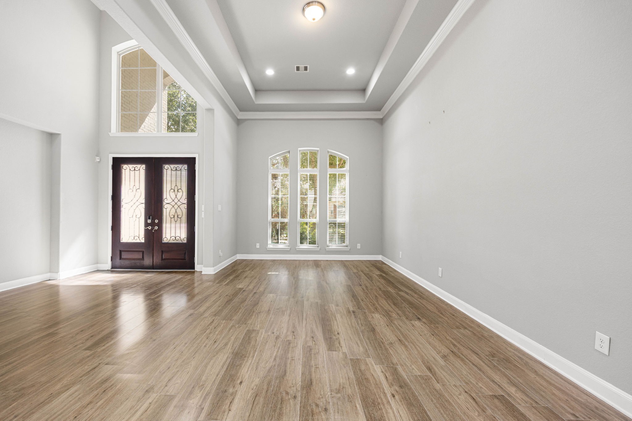 A tray ceiling and soaring arched window bring architectural detail to this versatile sitting area just off the foyer, ideal as a formal living space or additional flex room.