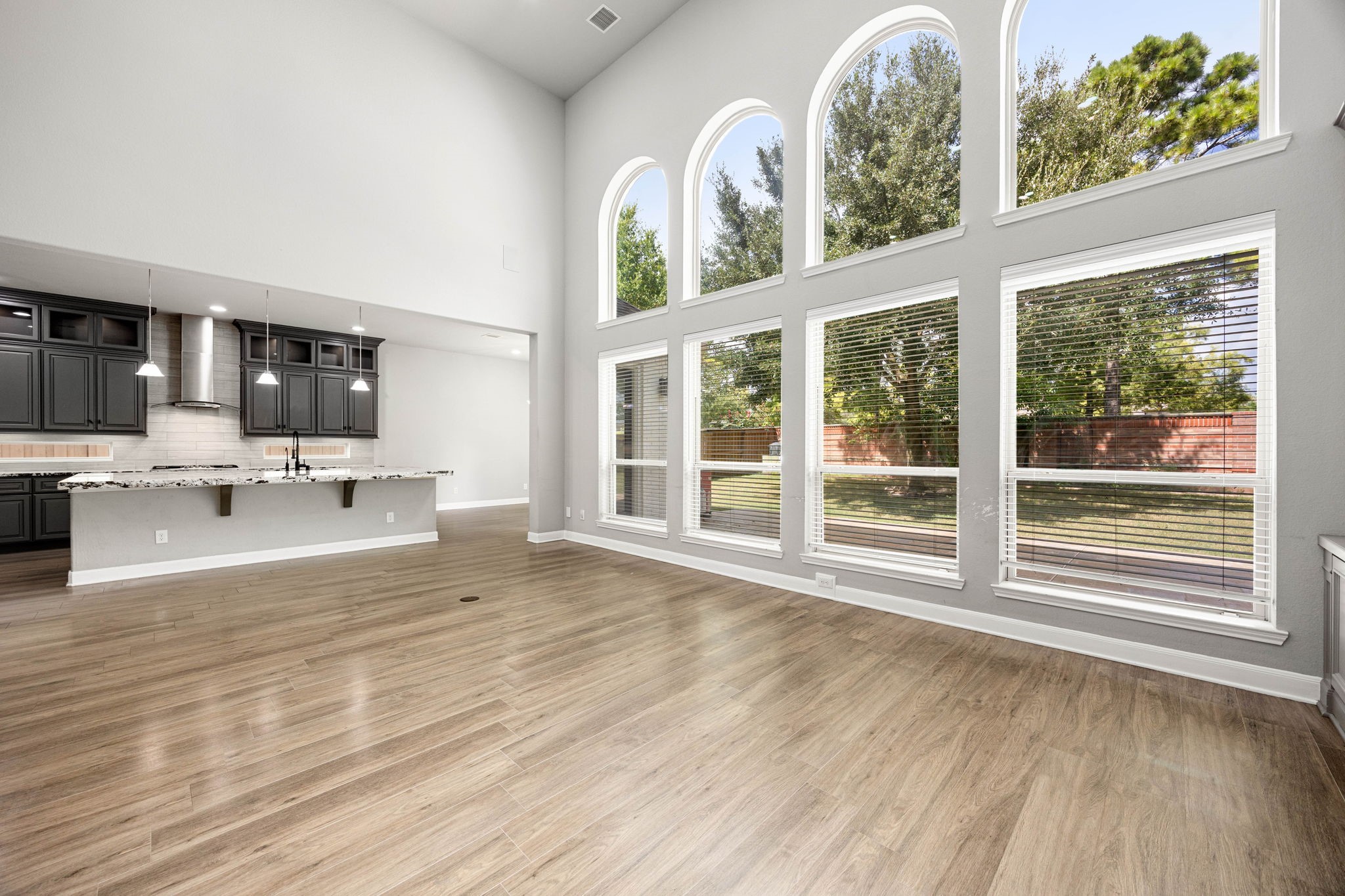 Floor-to-ceiling arched windows anchor this expansive open-concept living space, seamlessly connected to the kitchen for effortless everyday living and entertaining.