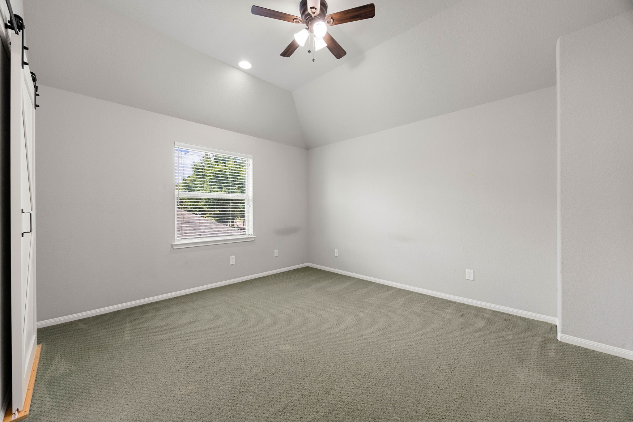 Vaulted ceilings and a large window bring extra volume and natural light to this generously sized secondary bedroom.