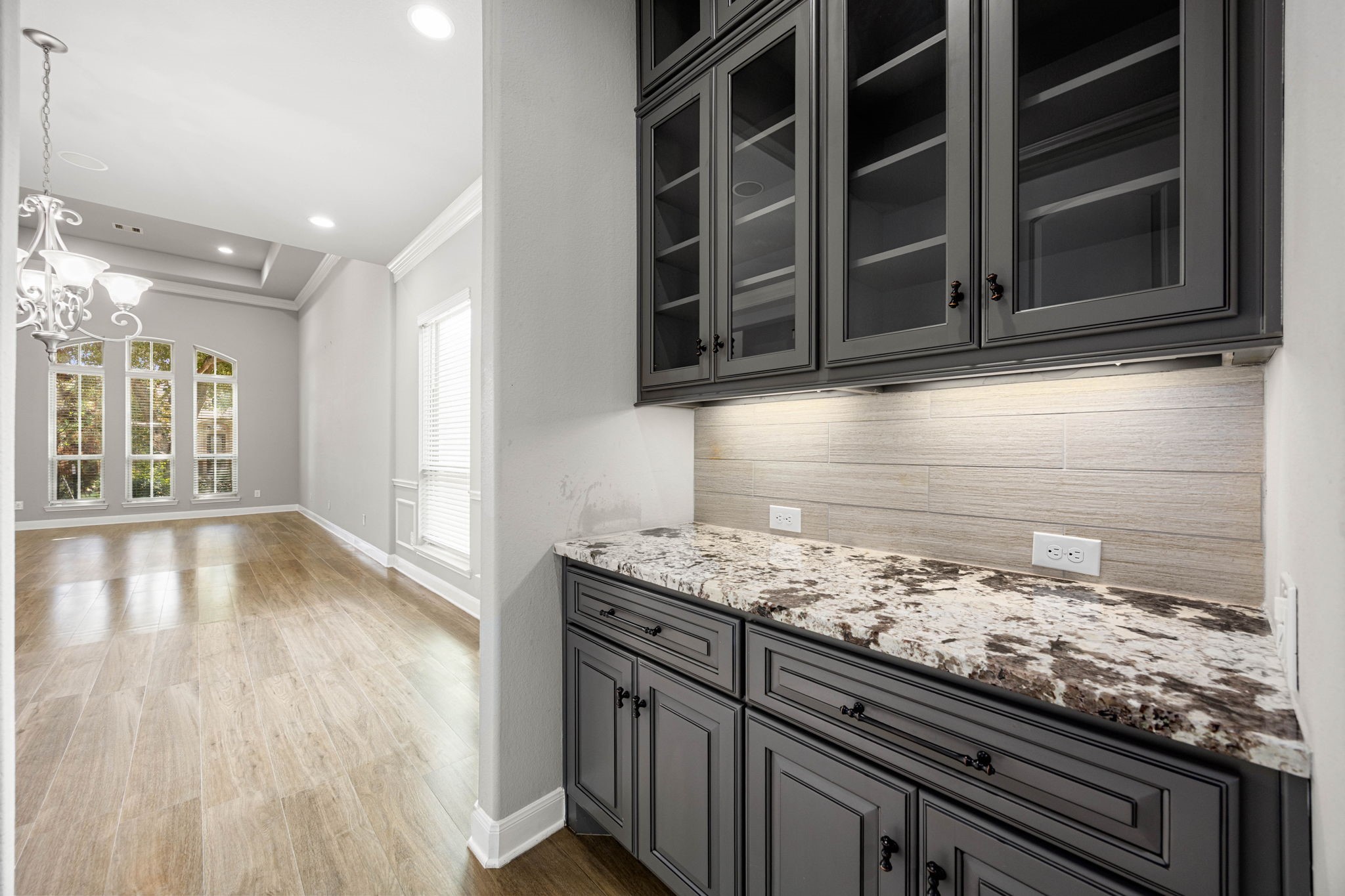 A butler's pantry connects the kitchen and dining area, offering striking counters and glass-front cabinetry for extra storage and easy serving between spaces.