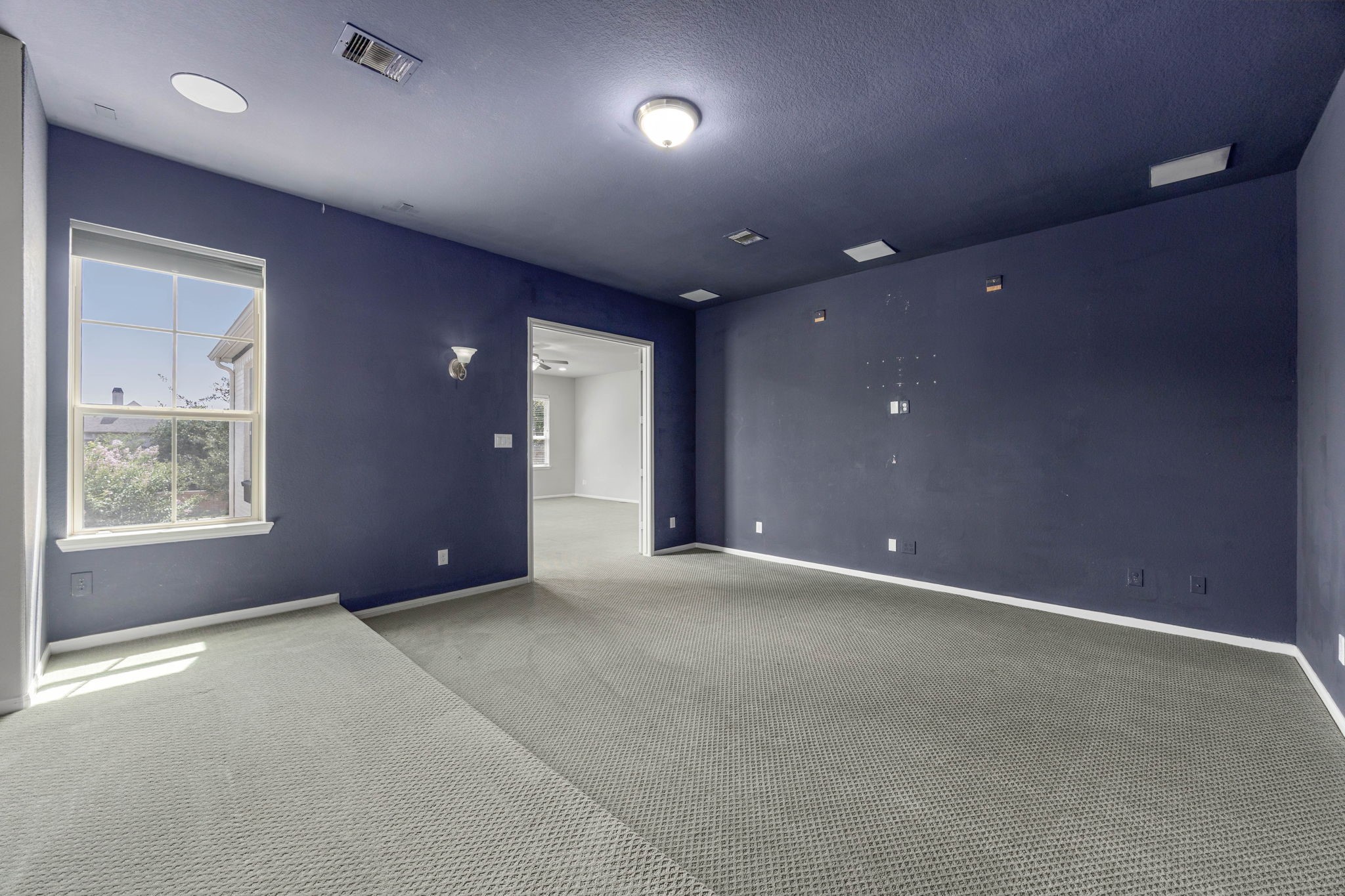 A dedicated media room features a raised platform for tiered seating, sconce lighting, and a bold accent wall  a ready-made space for movie nights.