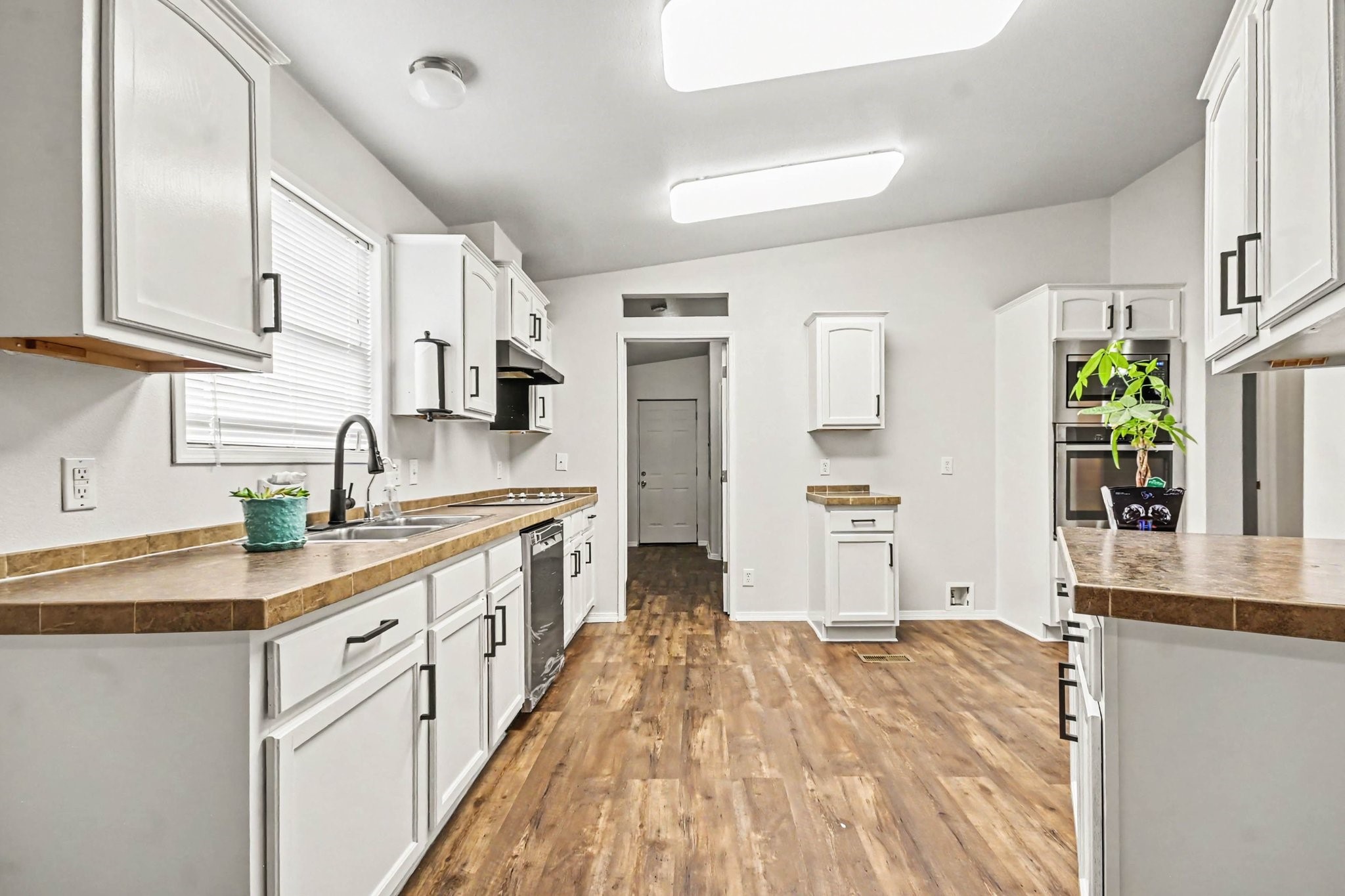 Newly painted kitchen has vinyl plank flooring, stainless appliances
