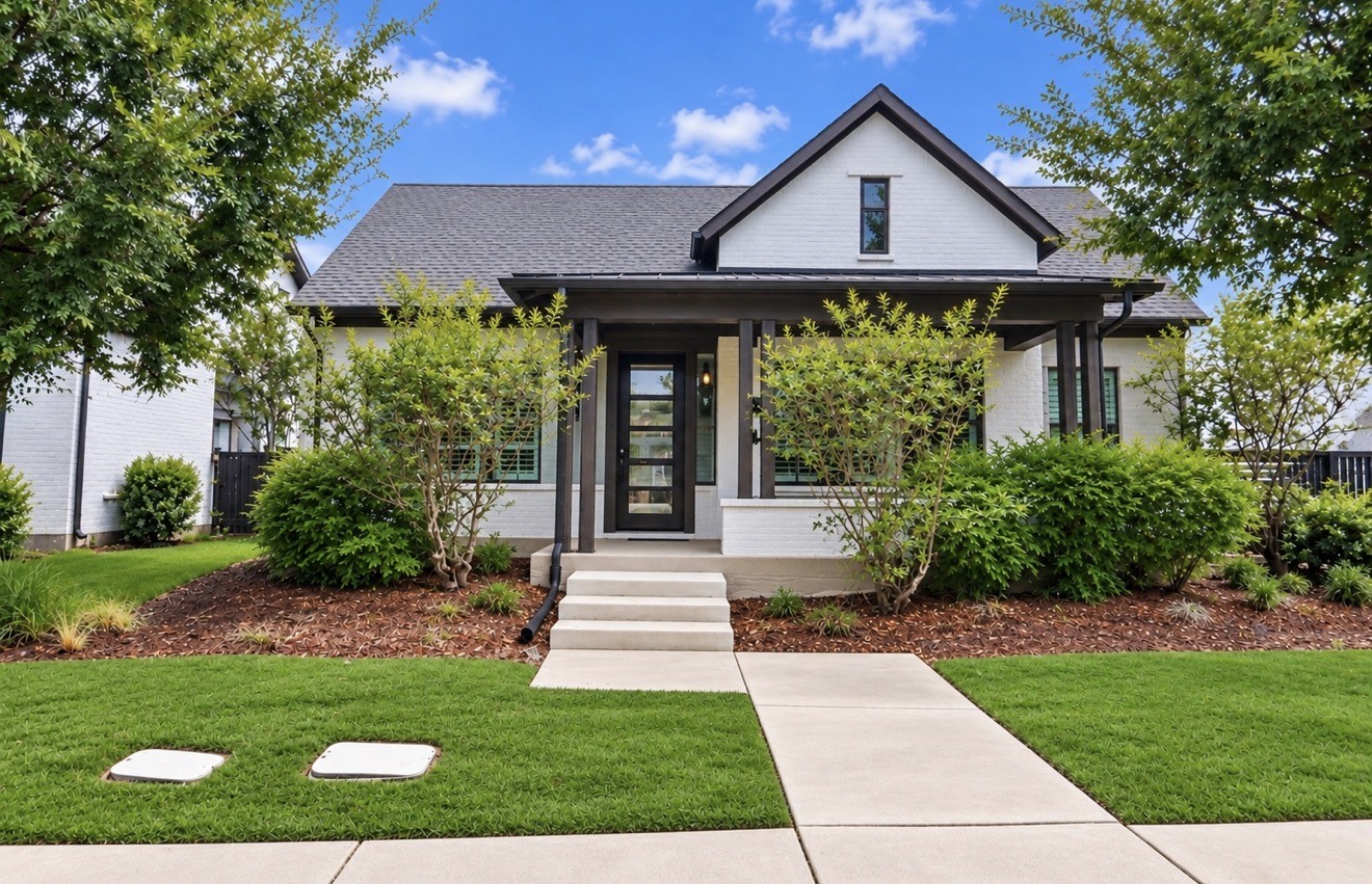 Striking curb appeal framed by mature trees, manicured landscaping and a welcoming covered entry.