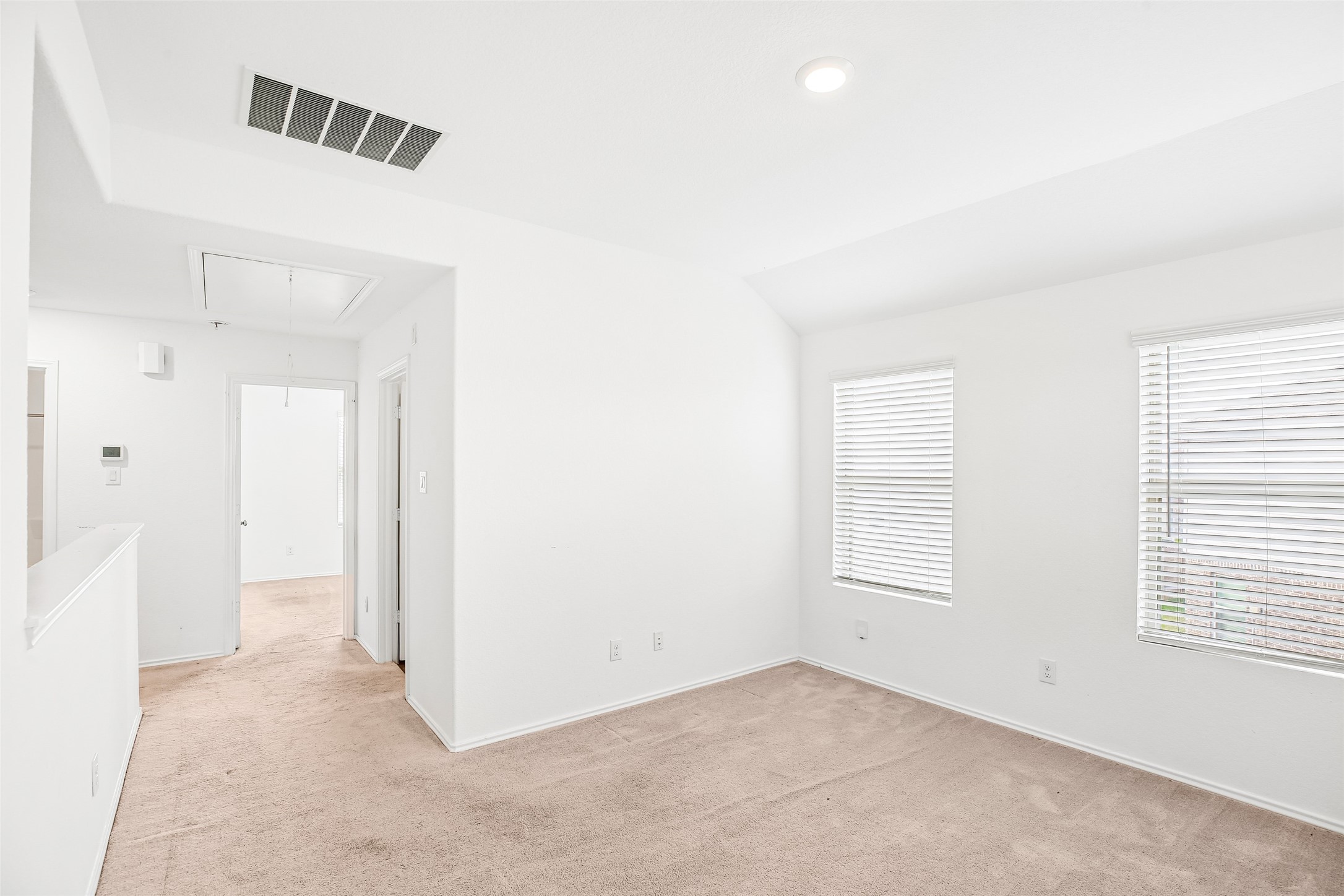 Upstairs family/flex area with two windows, existing carpet, and open access to the stair and adjacent rooms.