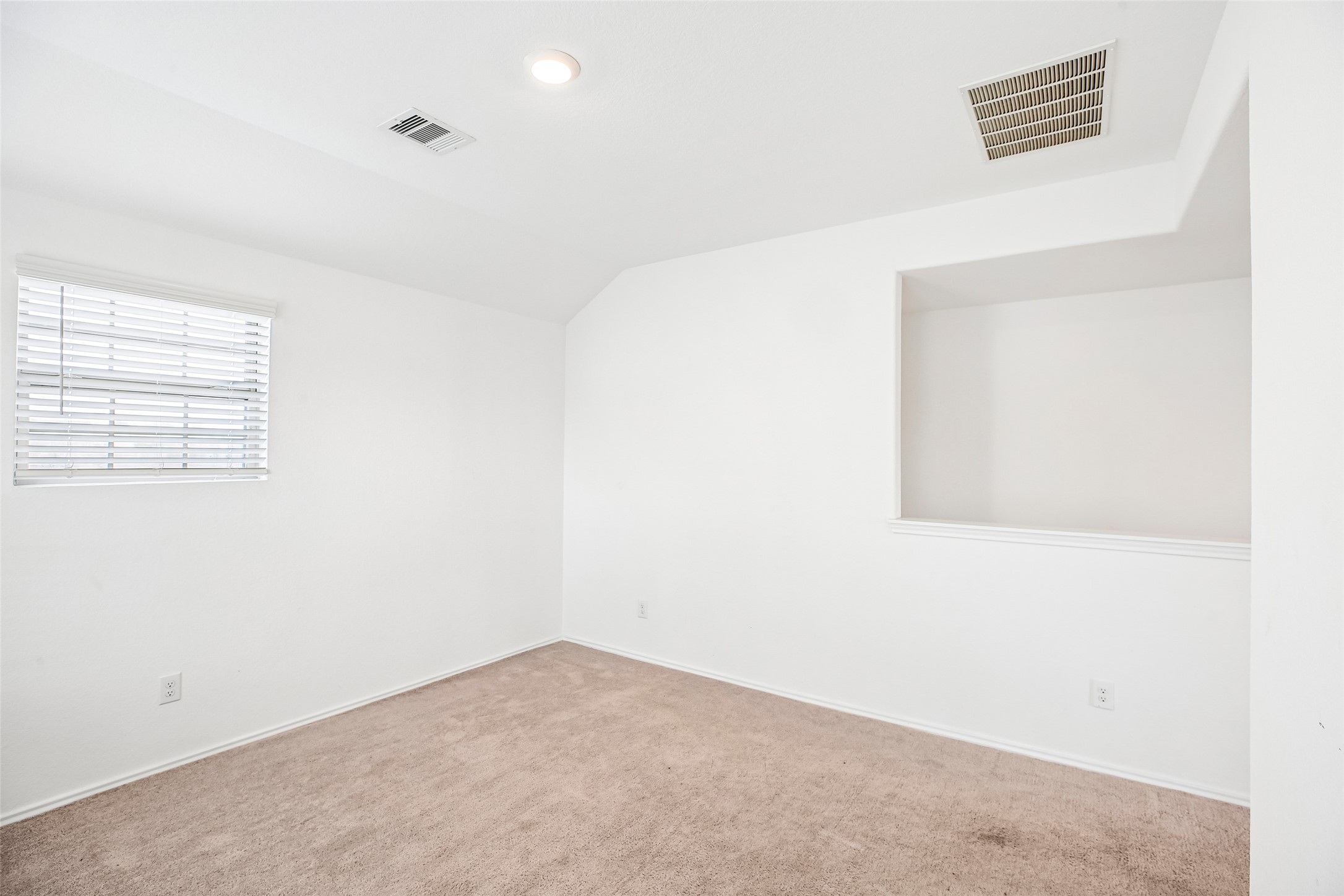 Upstairs family room with existing carpet, a window, ceiling vents, and an open stair-side half-wall.