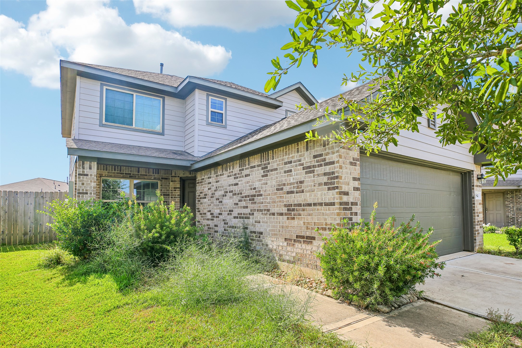 Front exterior view showing the home's brick-and-siding facade, entry, garage, driveway, and landscaped lawn.