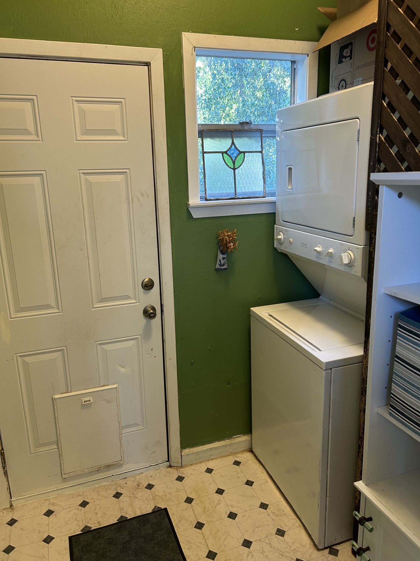 Utility room with stacked washer dryer and back door.