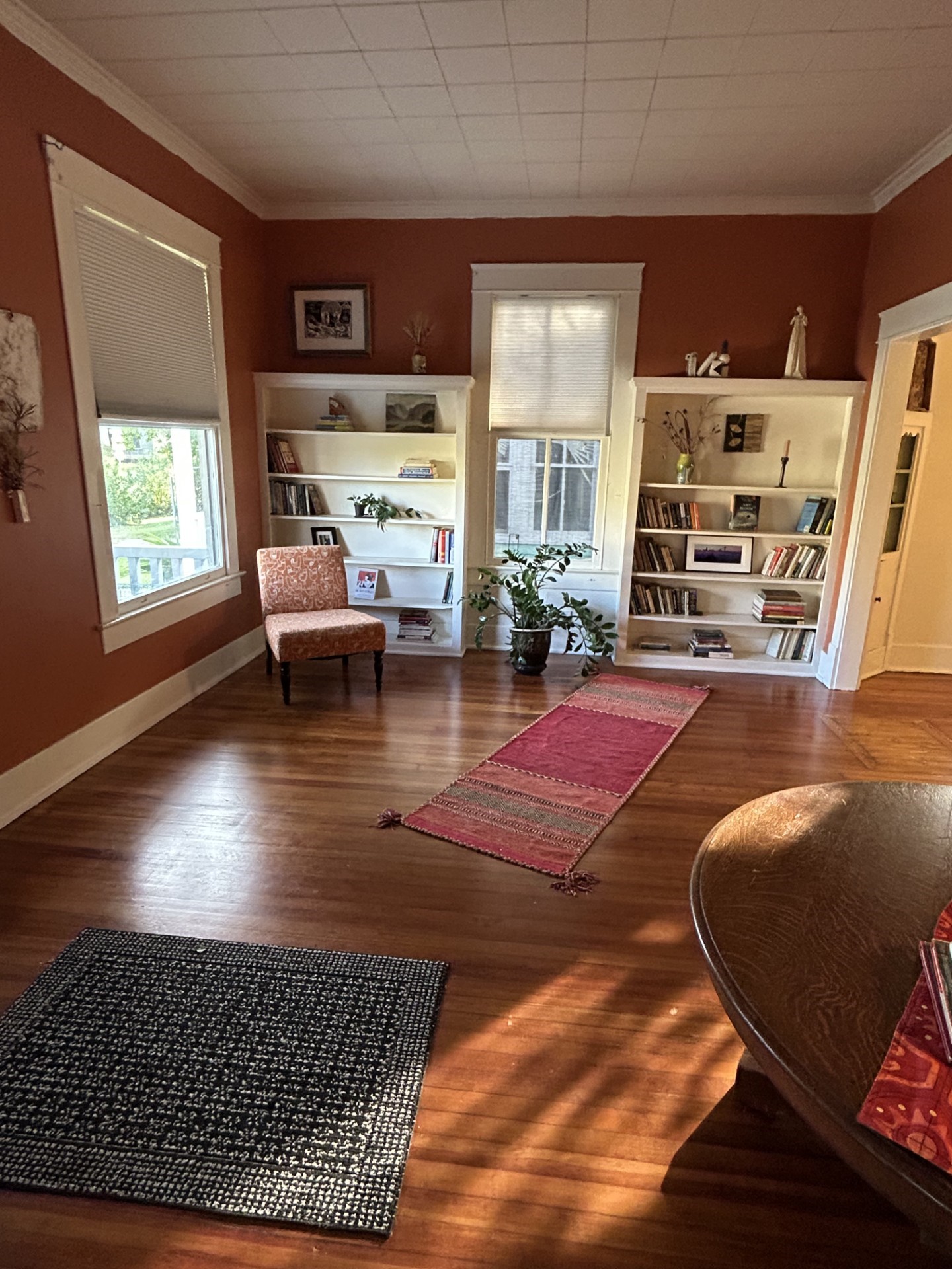 Living room with morning natural light. Bookcases along the east side. Quartersawn original longleaf pine floors. Dining room to the right.