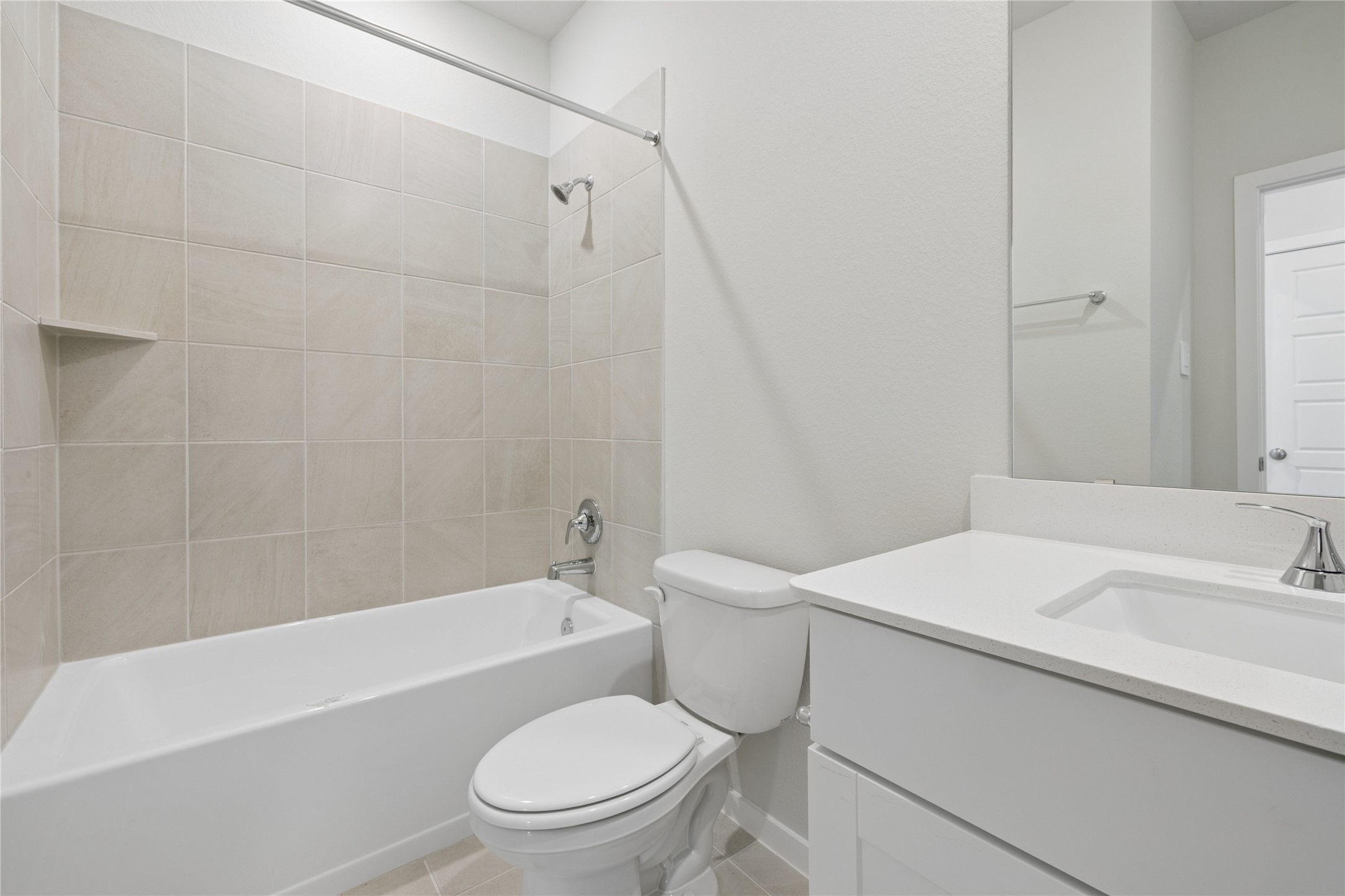 Modern bathroom featuring a sleek vanity with ample storage, a spacious bathtub with neutral tile surround, and bright lighting.