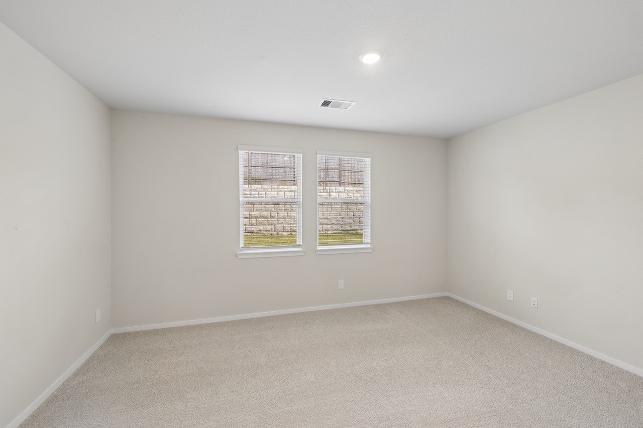 Bright, spacious room with neutral walls and carpeting, featuring two windows that invite natural light.