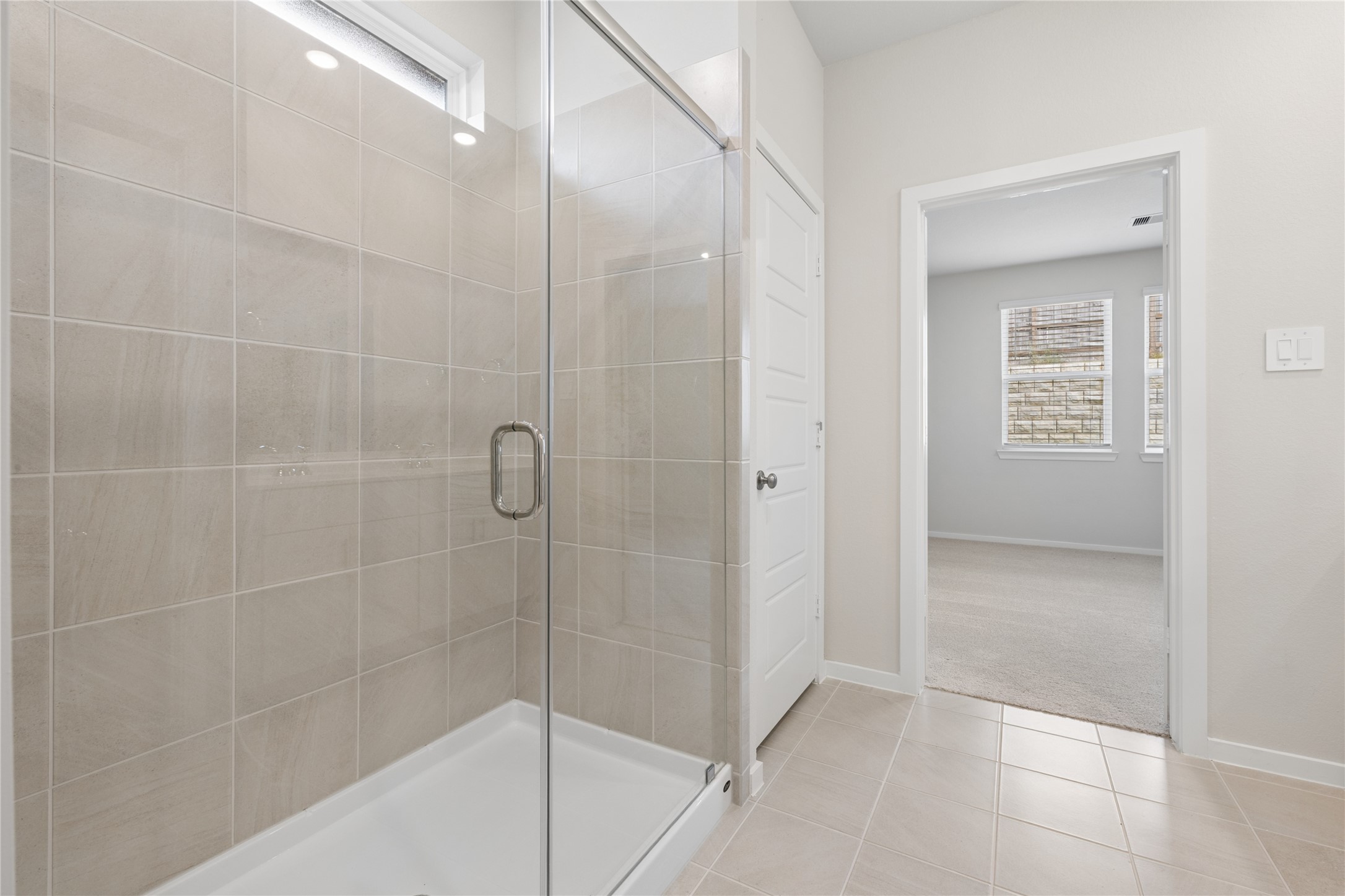 Spacious bathroom features a modern glass-enclosed shower with elegant tile work.