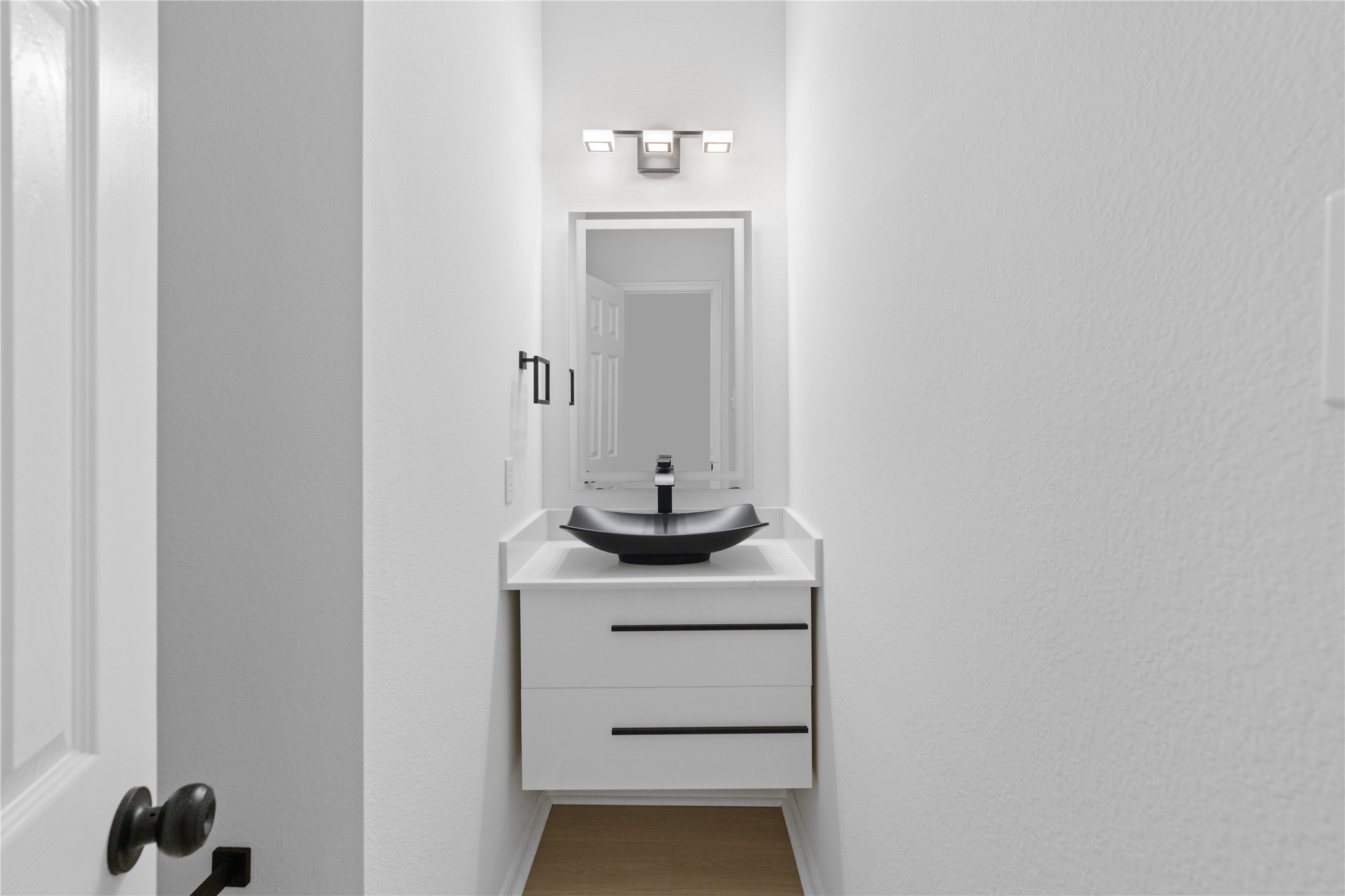 Powder Room  Sleek powder room with a floating-style vanity, vessel sink, modern rectangular mirror, and contrasting black fixtures.